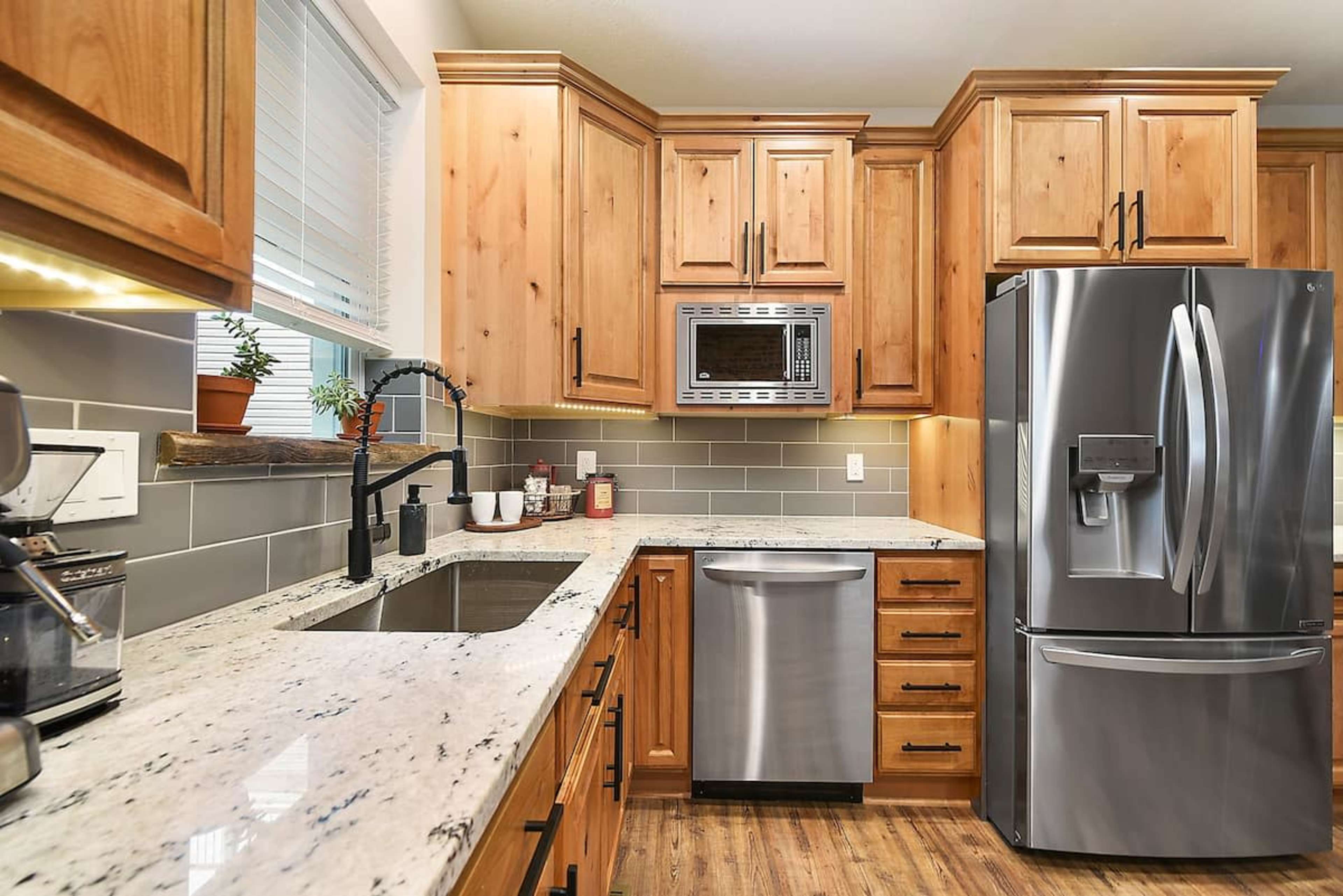 The kitchen features wooden cabinets, stainless steel appliances, a granite countertop, and a window above the sink.