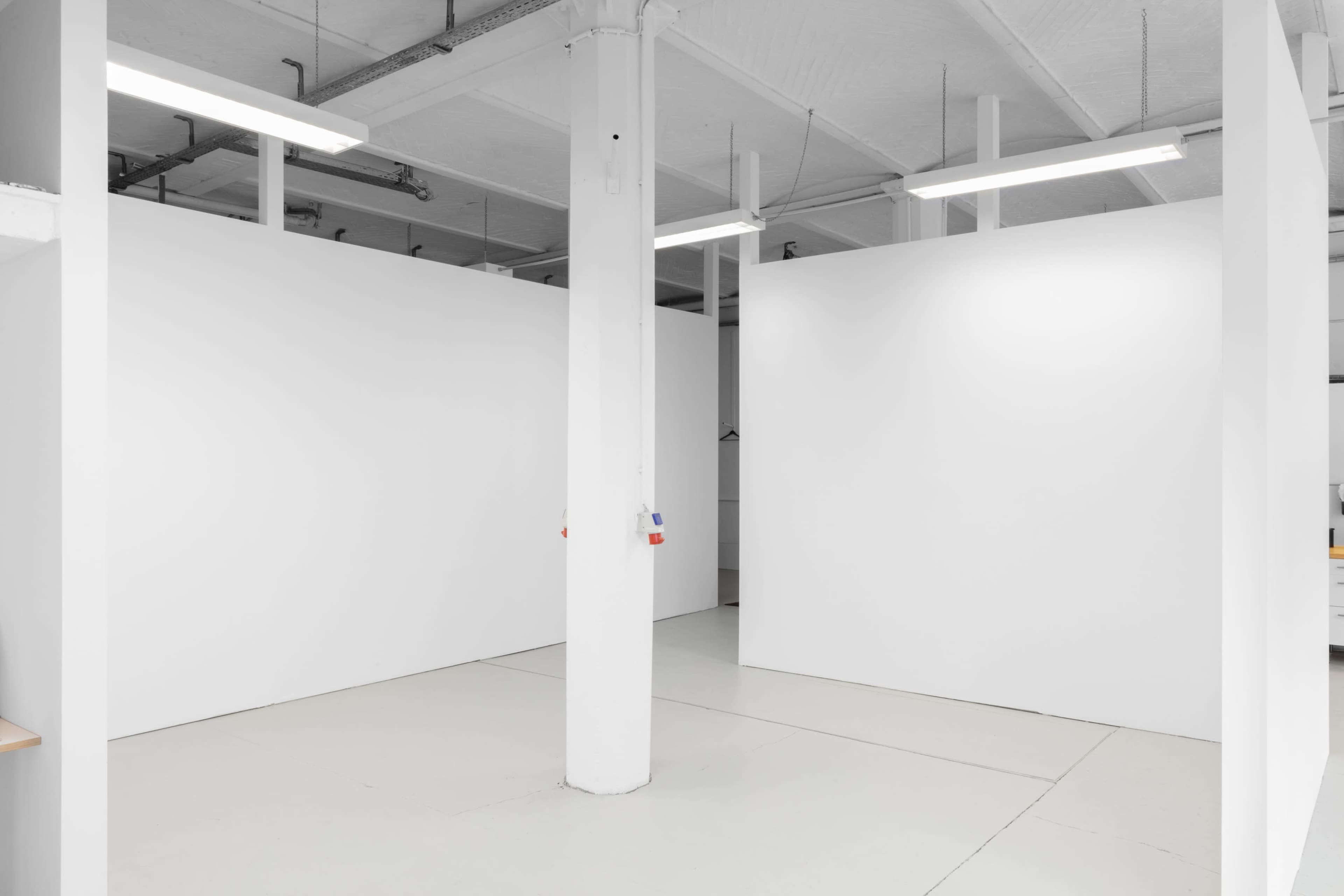 An empty room with white walls, a concrete floor, and a central support column.