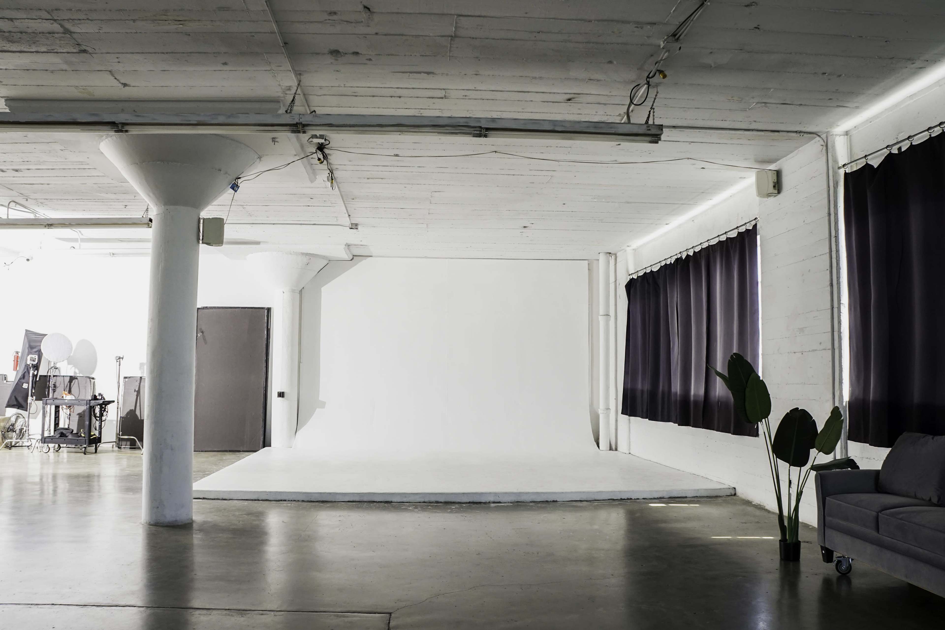 Blackout Loft Studio with central AC, a pre-lit corner cyc wall, Light Tunnel, wooden platform, white wooden reclaimed wall & frameless window with downtown view - PRO II Image in Central LA, Los Angeles, CA