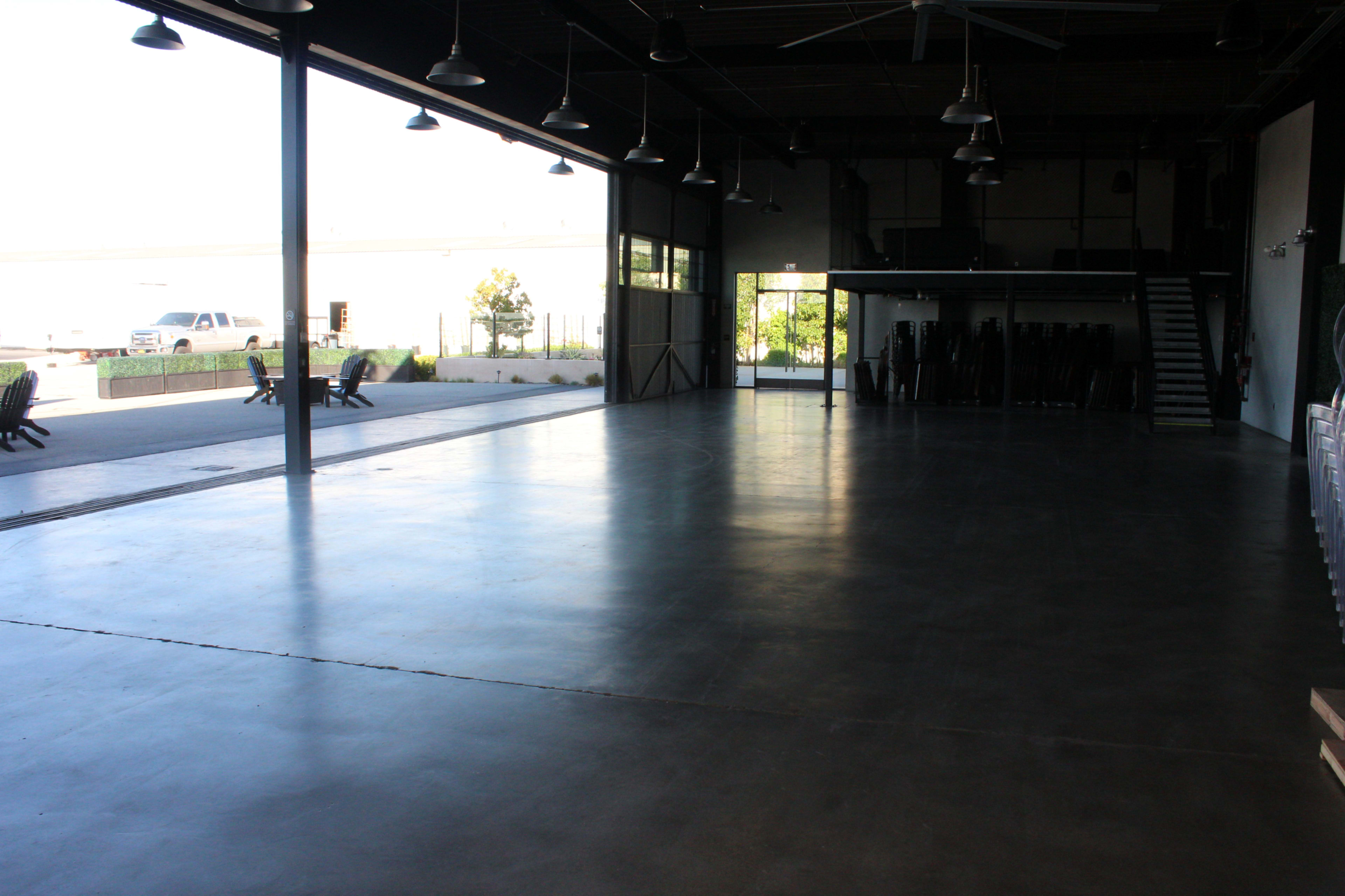 An empty industrial space with polished concrete floors and large windows letting in natural light.