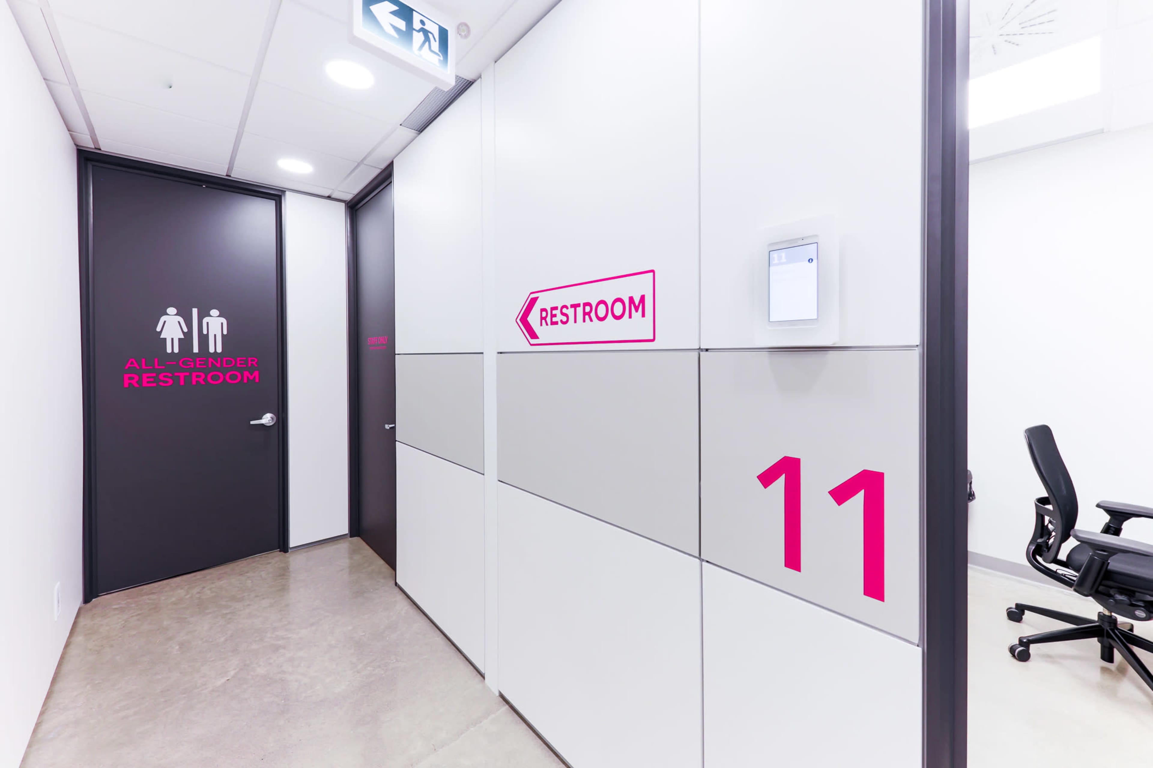 The image shows a hallway with a door labeled "ALL-GENDER RESTROOM" and a nearby wall unit marked with the number "11."
