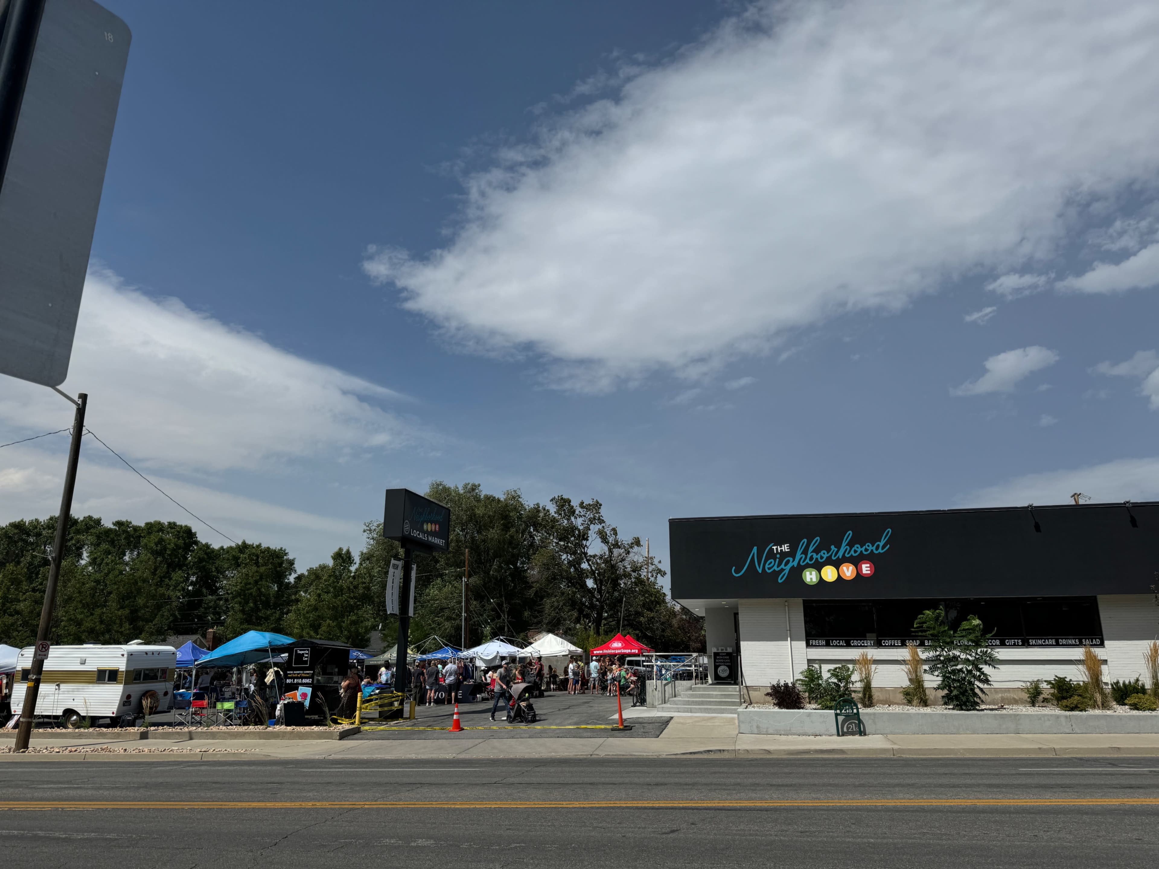 A variety of tents and booths set up for an event are visible outside a building named "The Neighborhood," with a clear blue sky overhead.