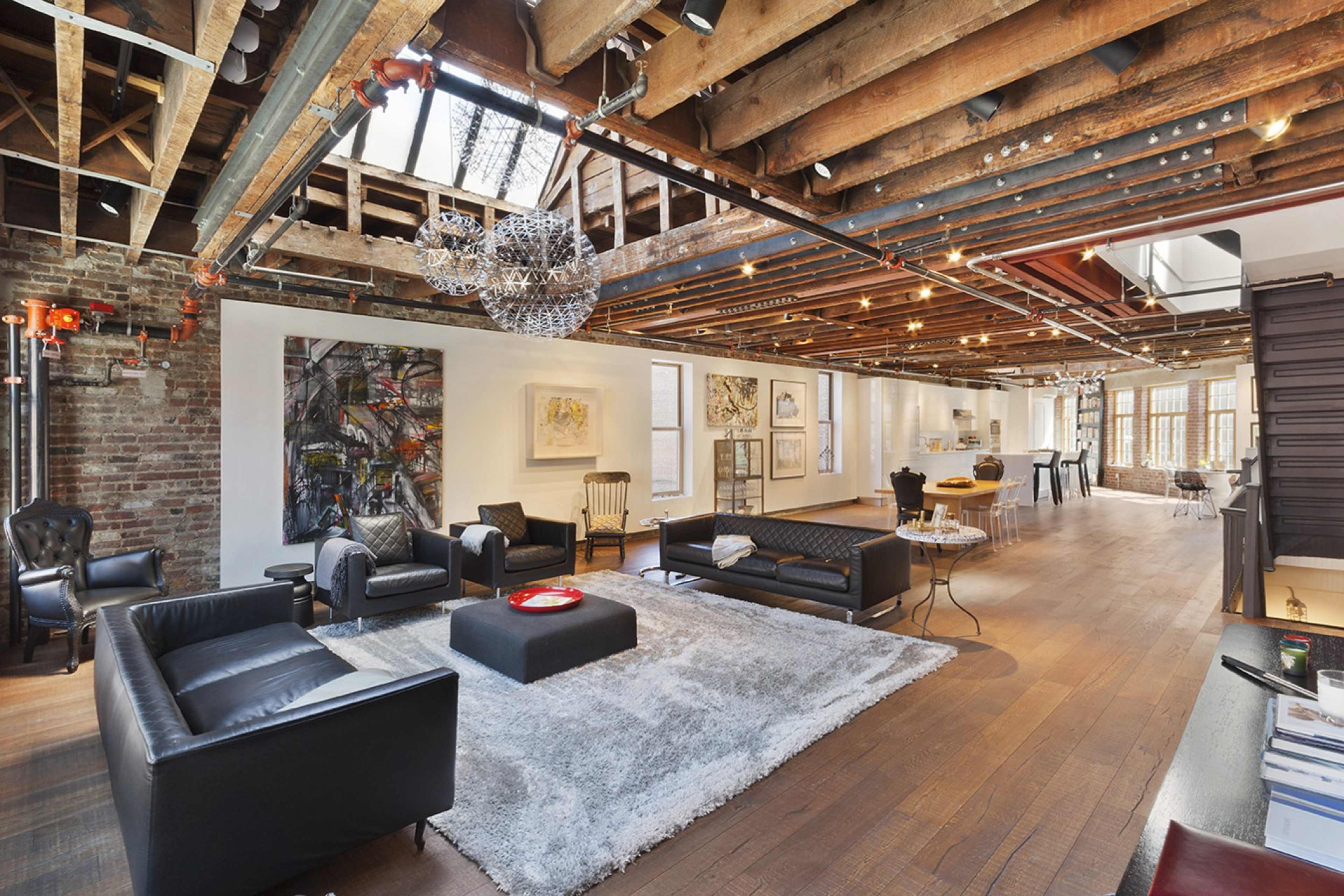 A spacious, open-concept living area with exposed wooden beams, modern furniture, and artwork displayed on the walls.
