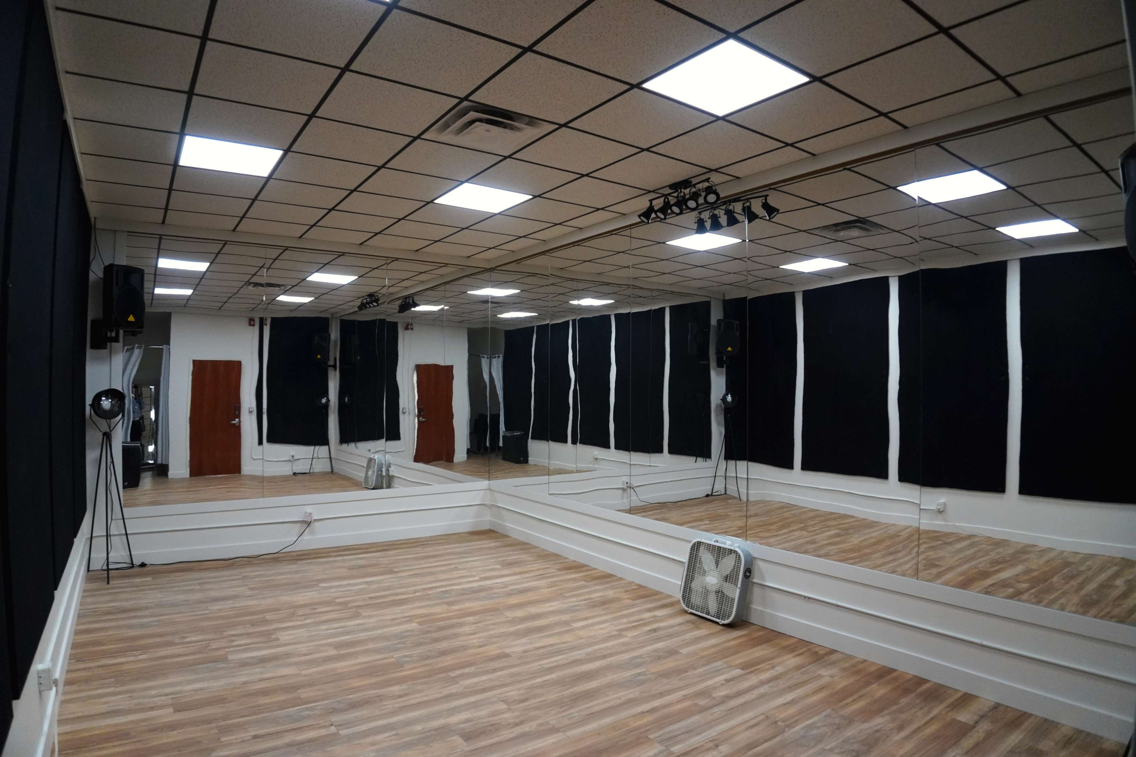 A dance studio features mirrored walls, wooden flooring, and black soundproof panels.