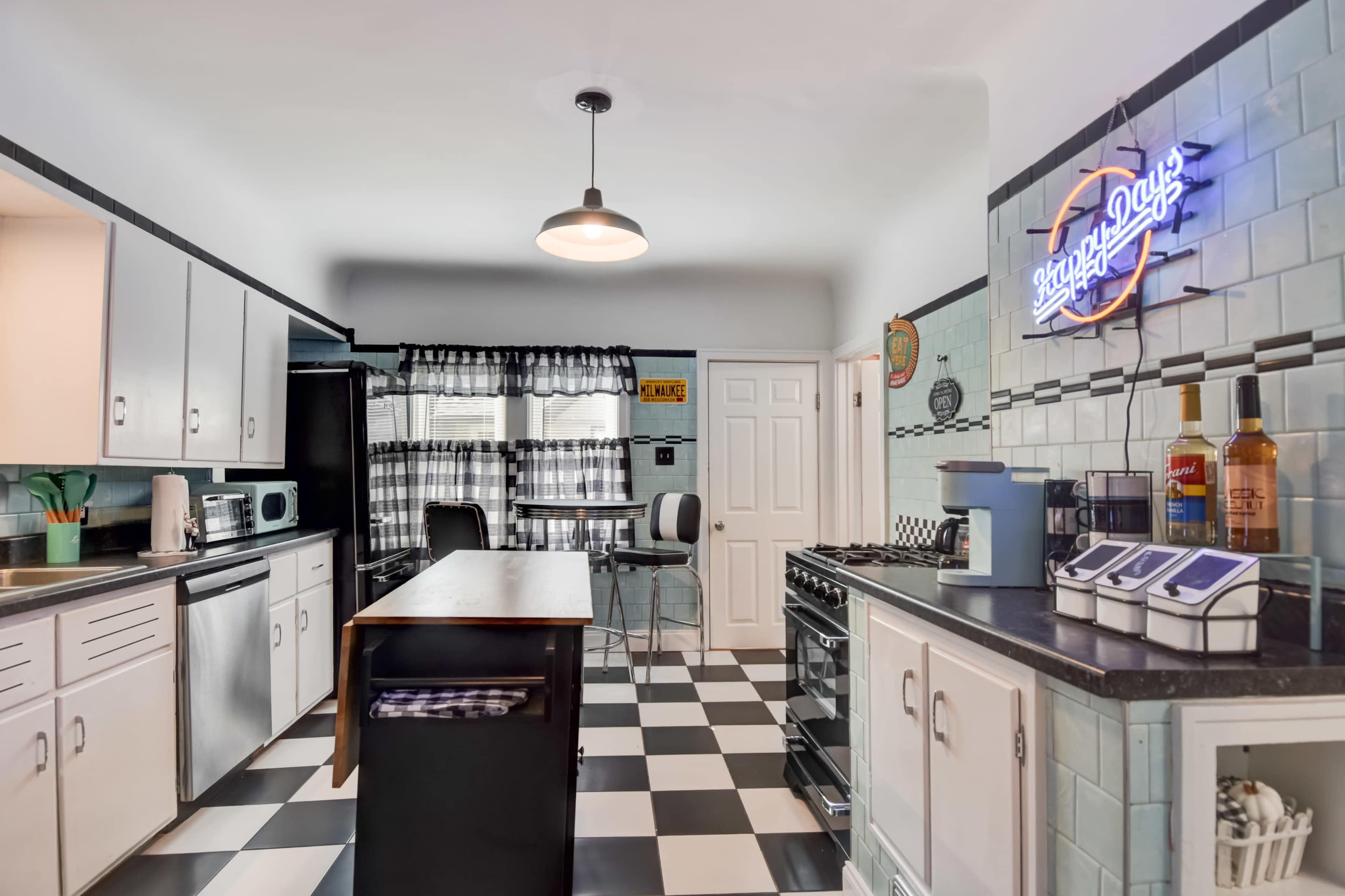 The kitchen features black and white checkered floors, a central island, and modern appliances alongside vintage decor.