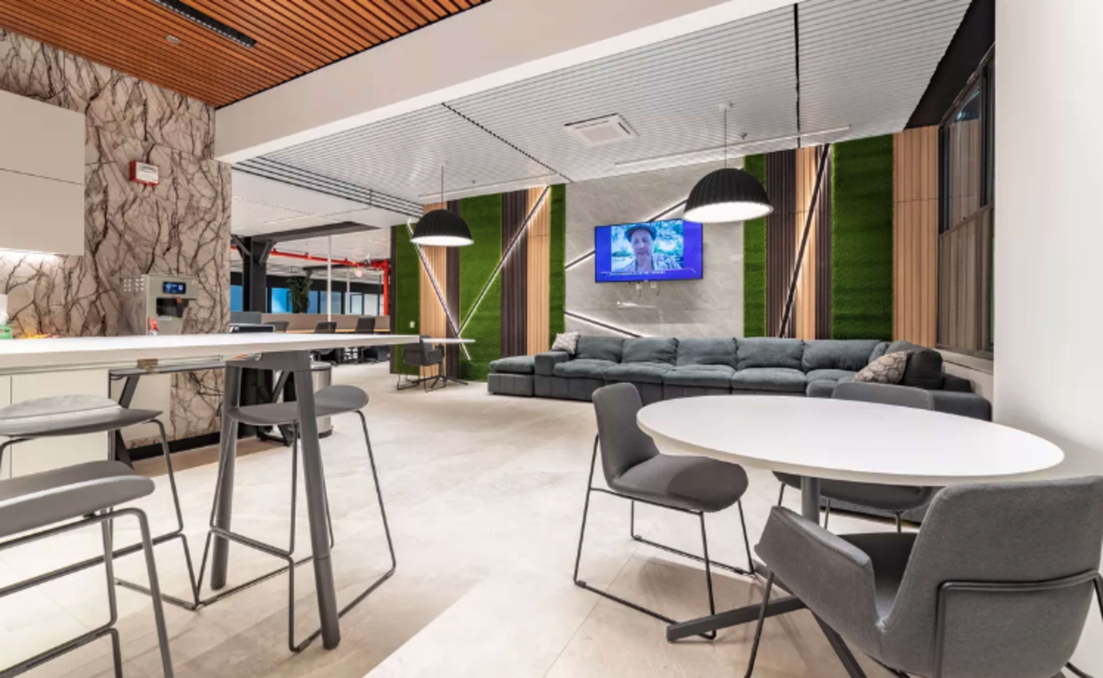 A modern interior space with a seating area, dining tables, and a television mounted on the wall.