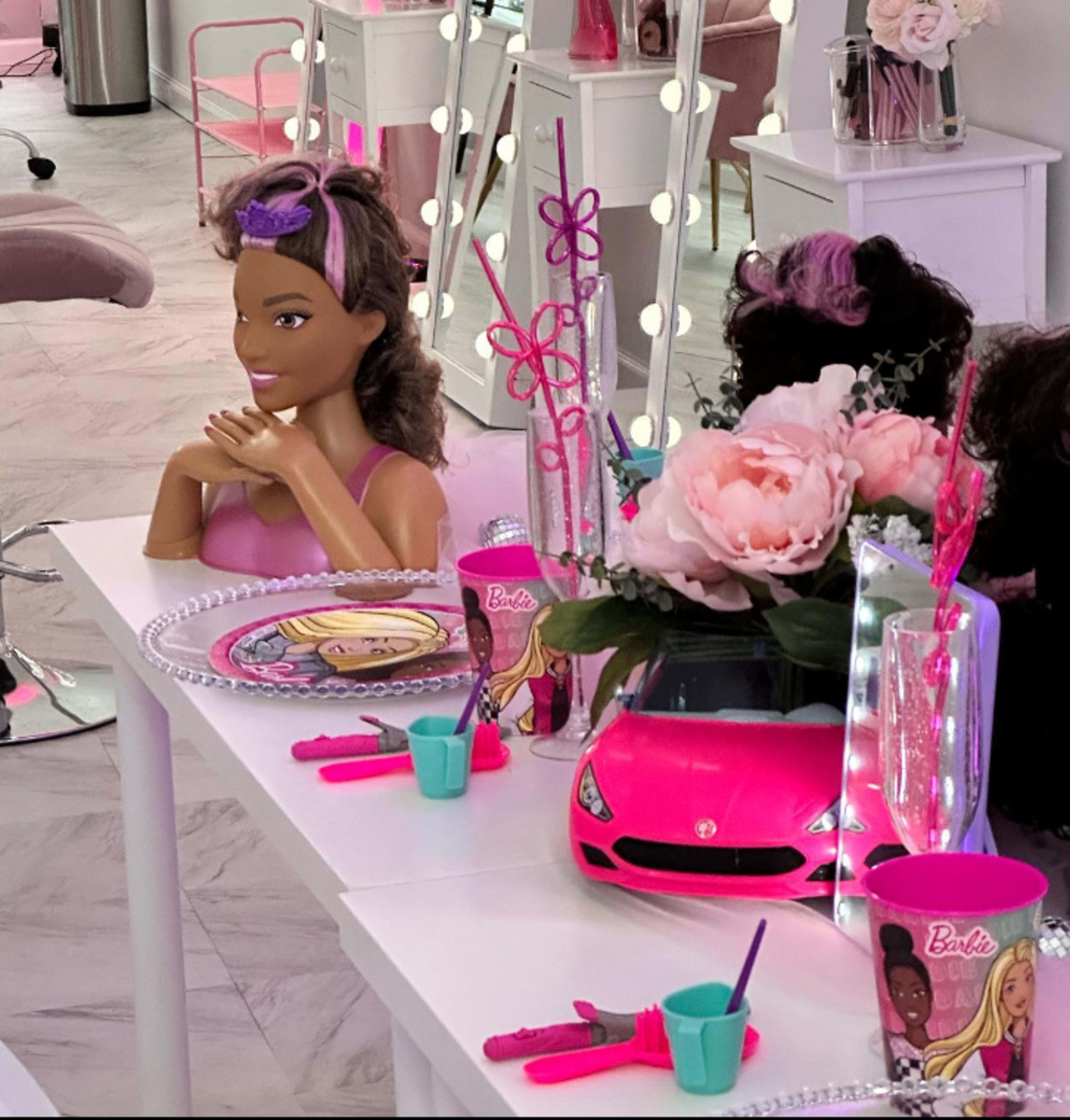 The scene features a brightly decorated room with a table set for a themed party, including a Barbie doll, pink decorations, and various accessories.