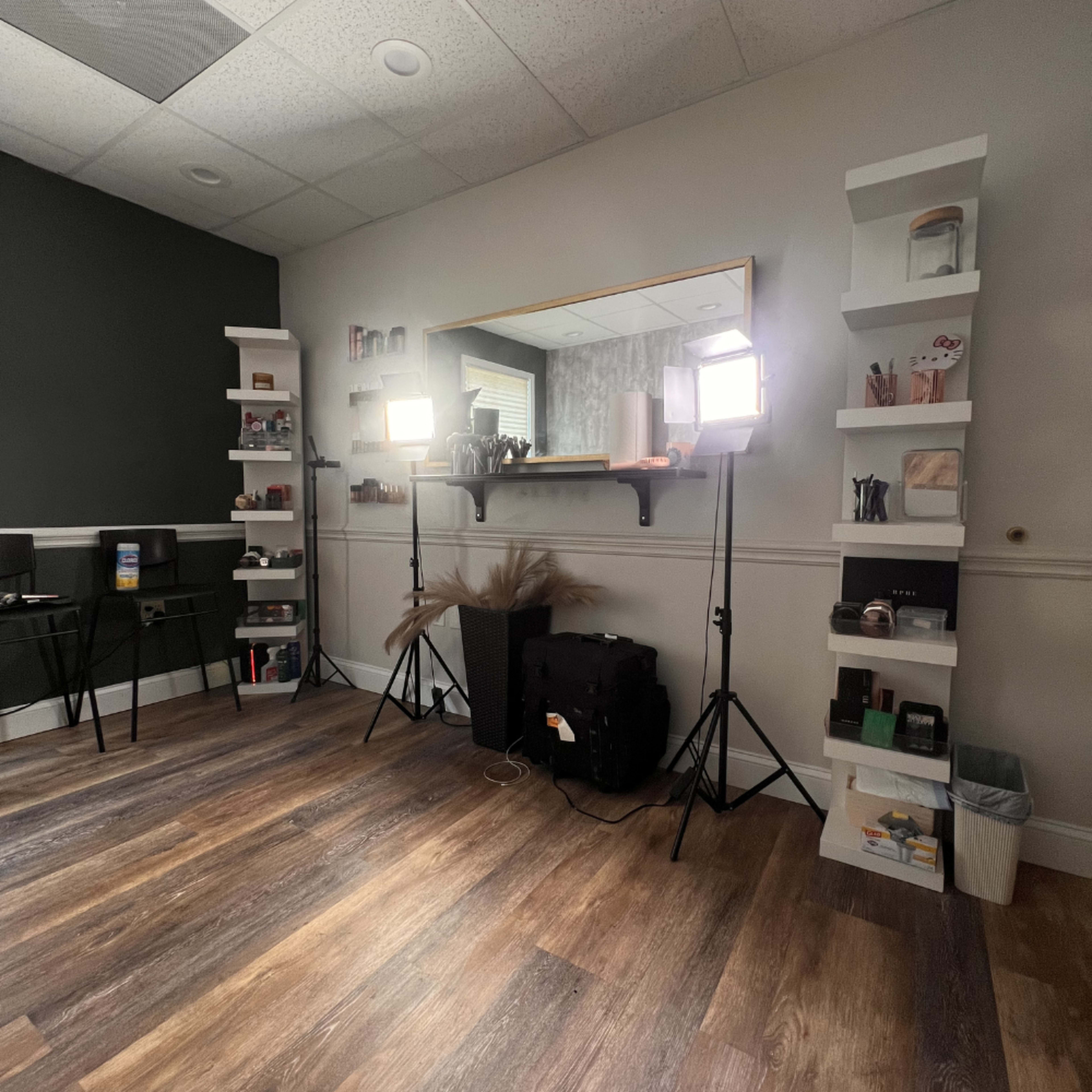 The image shows a well-lit room with two softbox lights positioned near a mirror, flanked by shelves containing various beauty and personal care products.