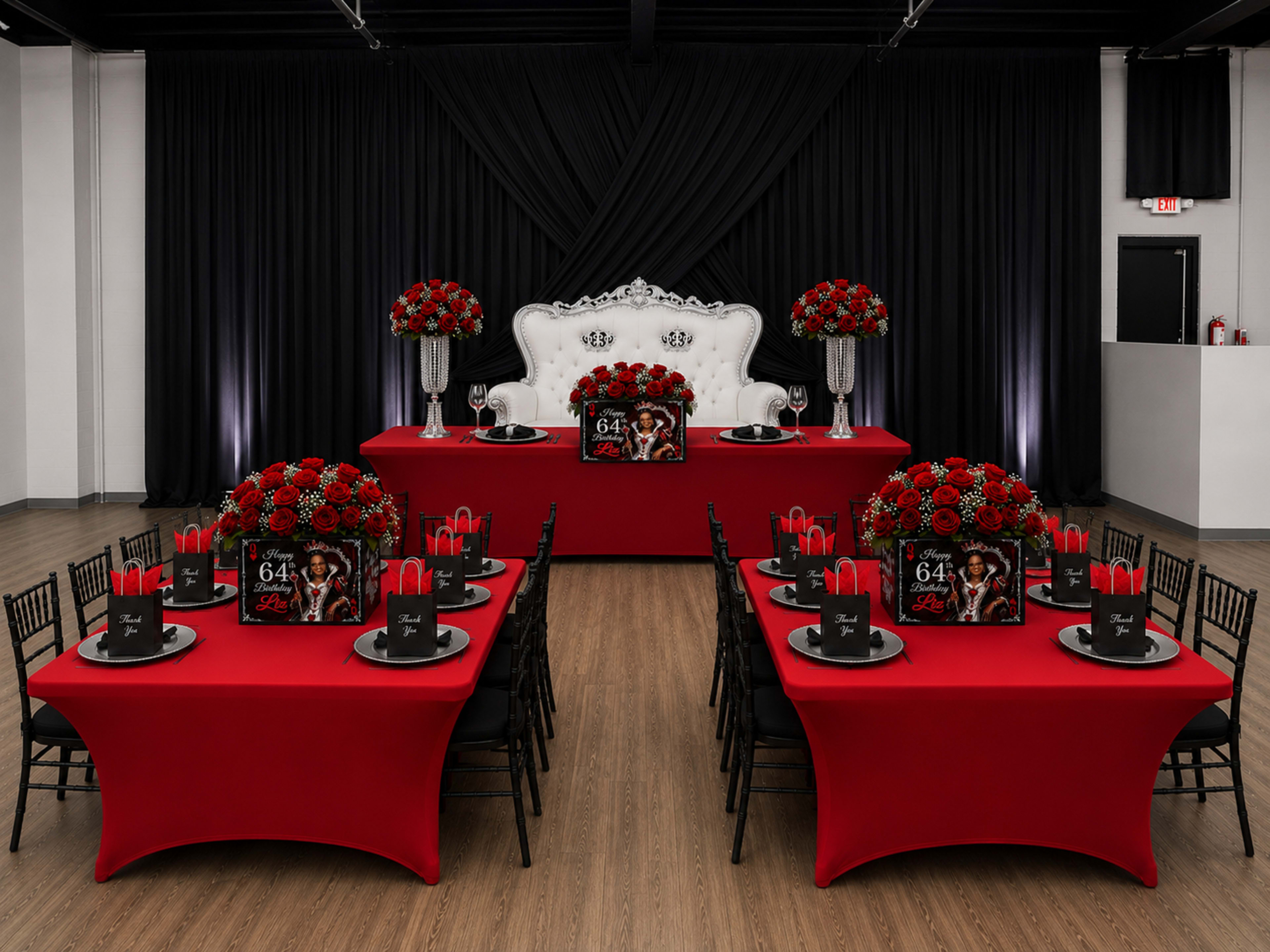The image shows an elegantly decorated event space with a red and black theme, featuring tables adorned with black chairs, vibrant red roses, and stylish centerpieces.