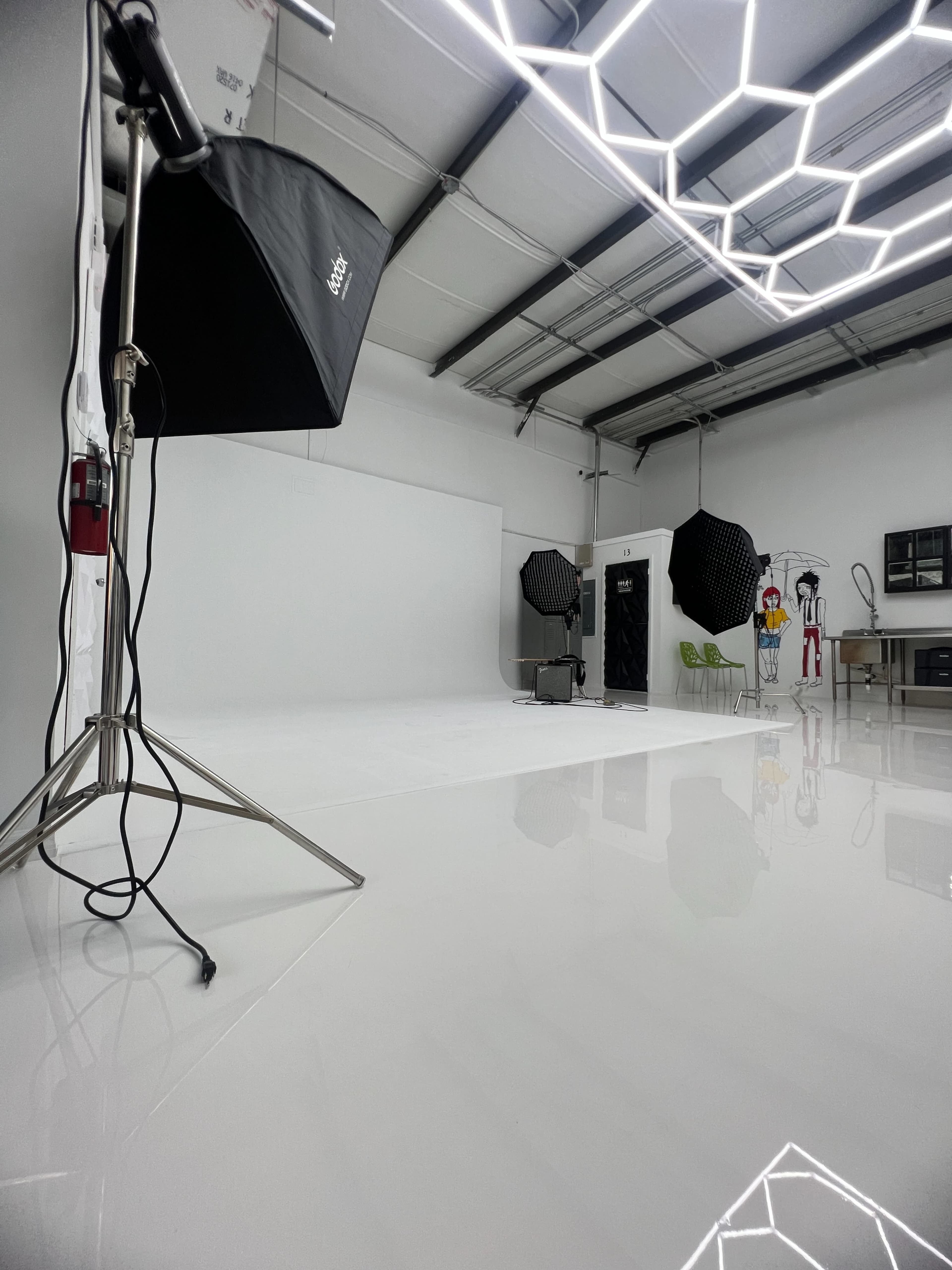 A photography studio equipped with lighting equipment, a white backdrop, and various props.