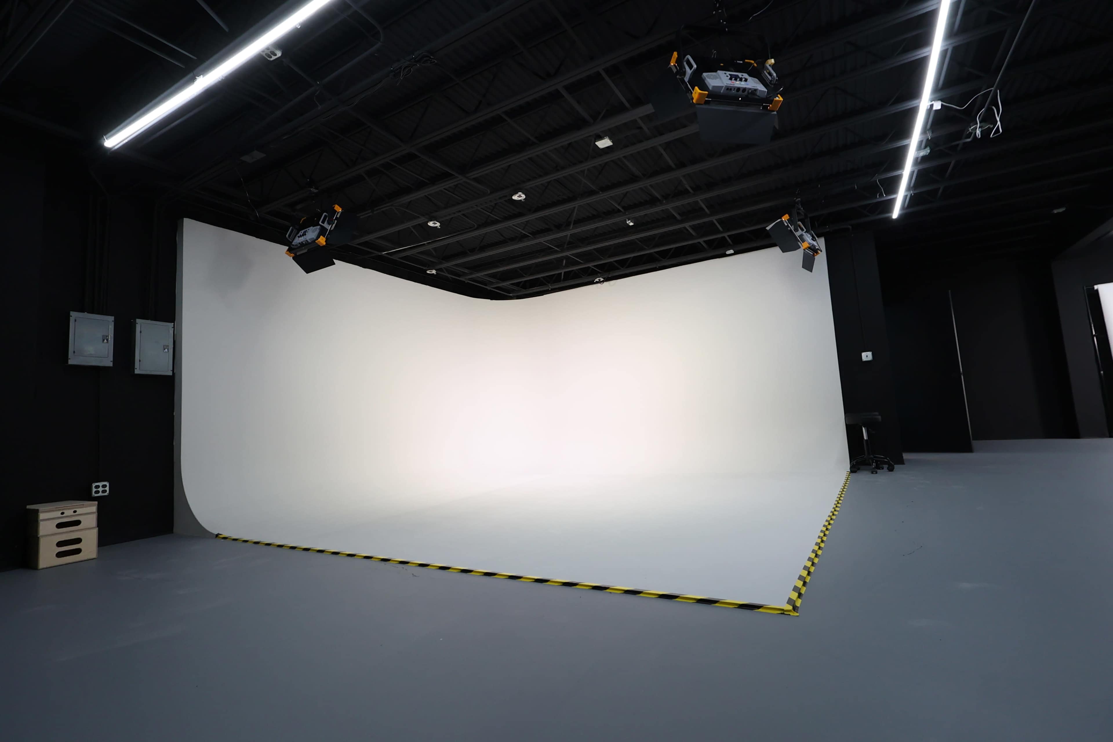 The image shows a photography studio with a curved white backdrop and bright overhead lights.