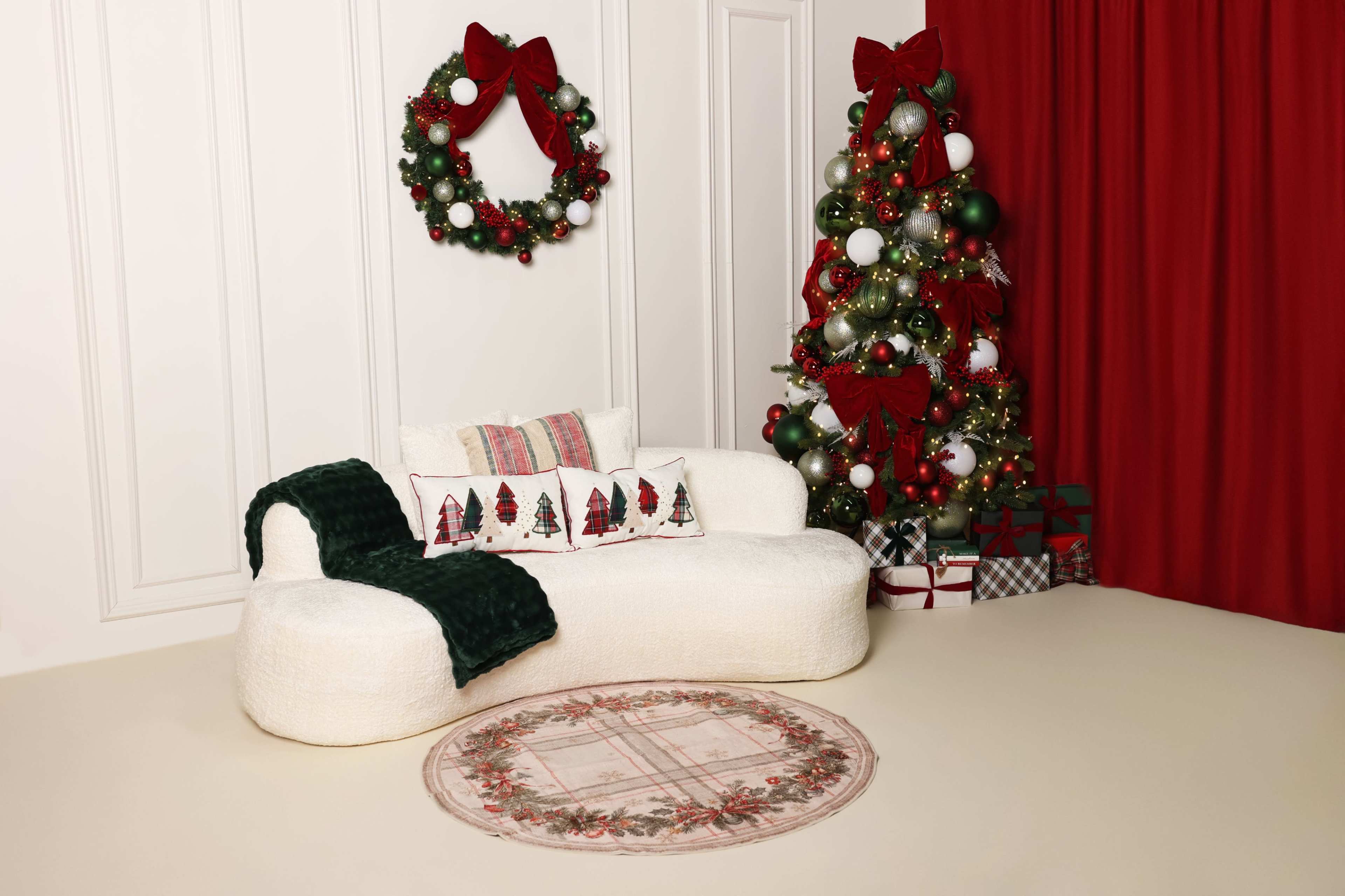 A cozy, modern white sofa is placed in a festive room decorated with a Christmas wreath, a decorated tree, and wrapped gifts.