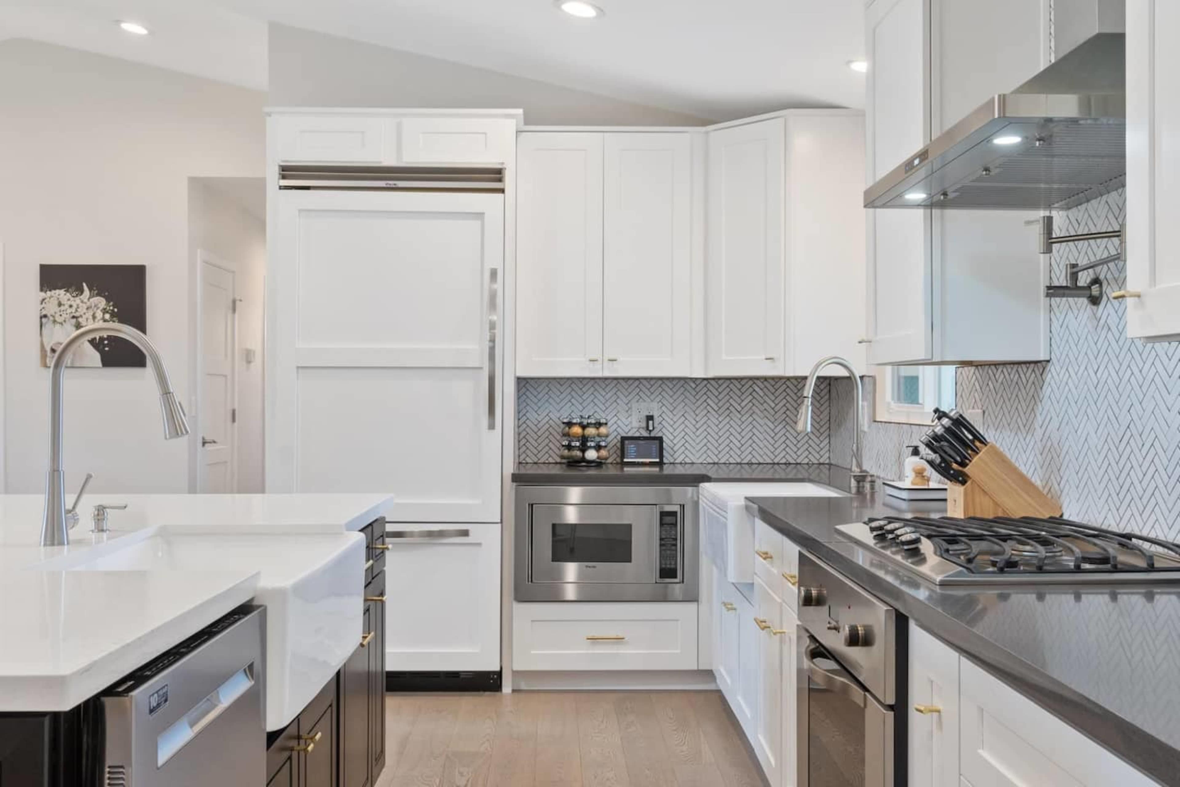 A modern kitchen featuring white cabinets, stainless steel appliances, and a dark countertop with a gas stove.