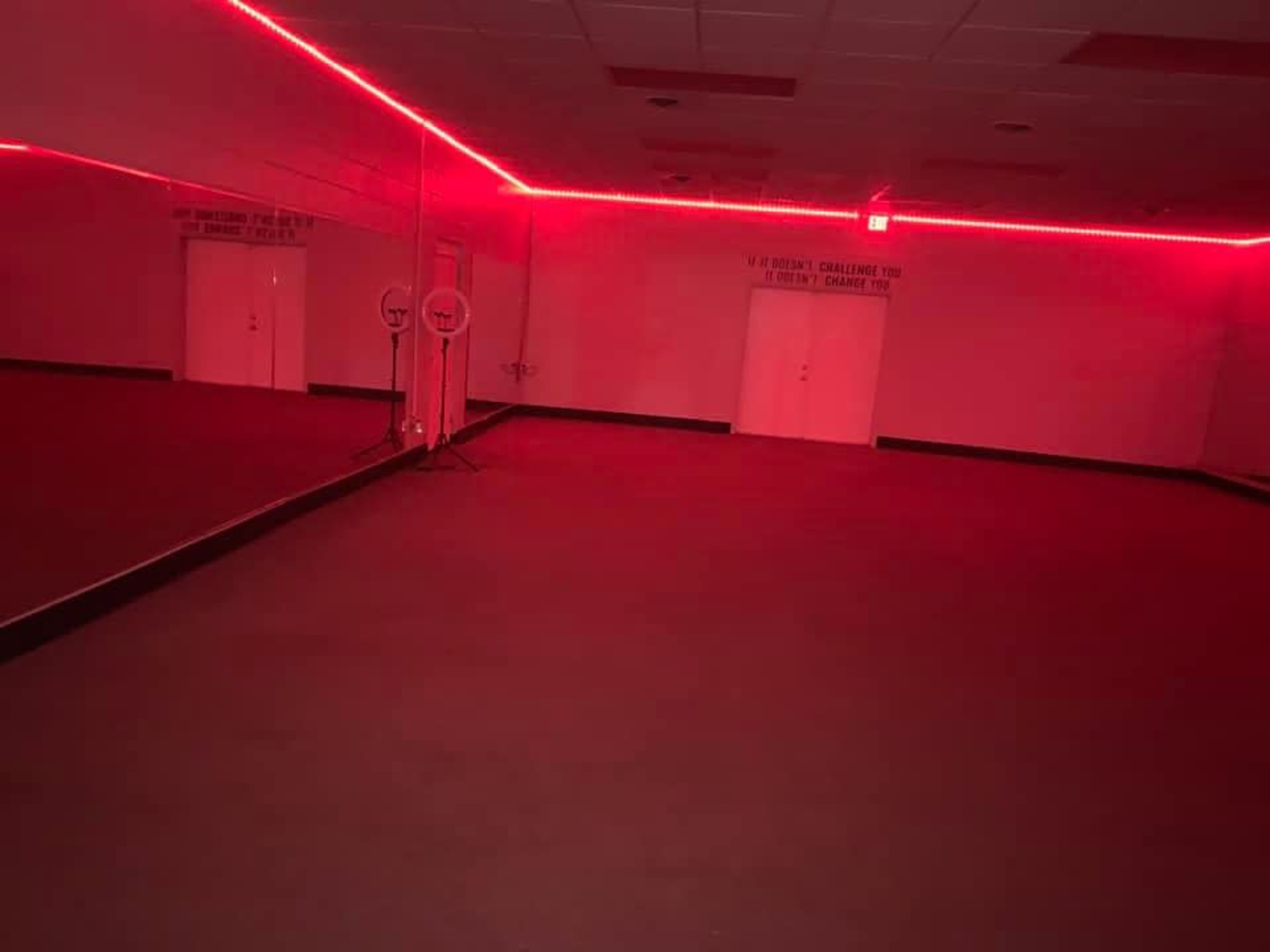 A dimly lit room with red LED lights along the walls and a large mirror on one side.