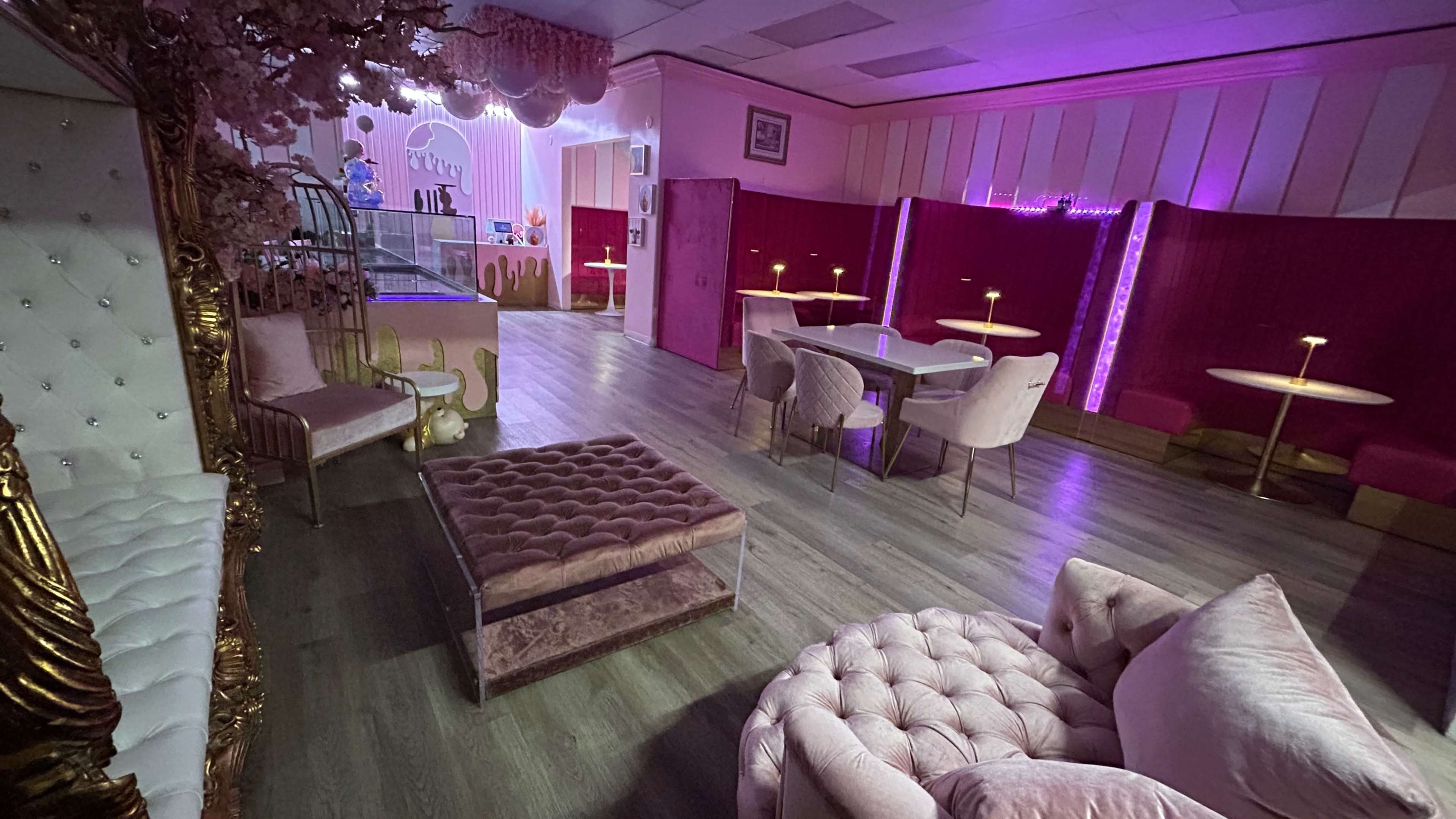 The image shows a stylized café interior with pink decor, plush seating, and ambient lighting.