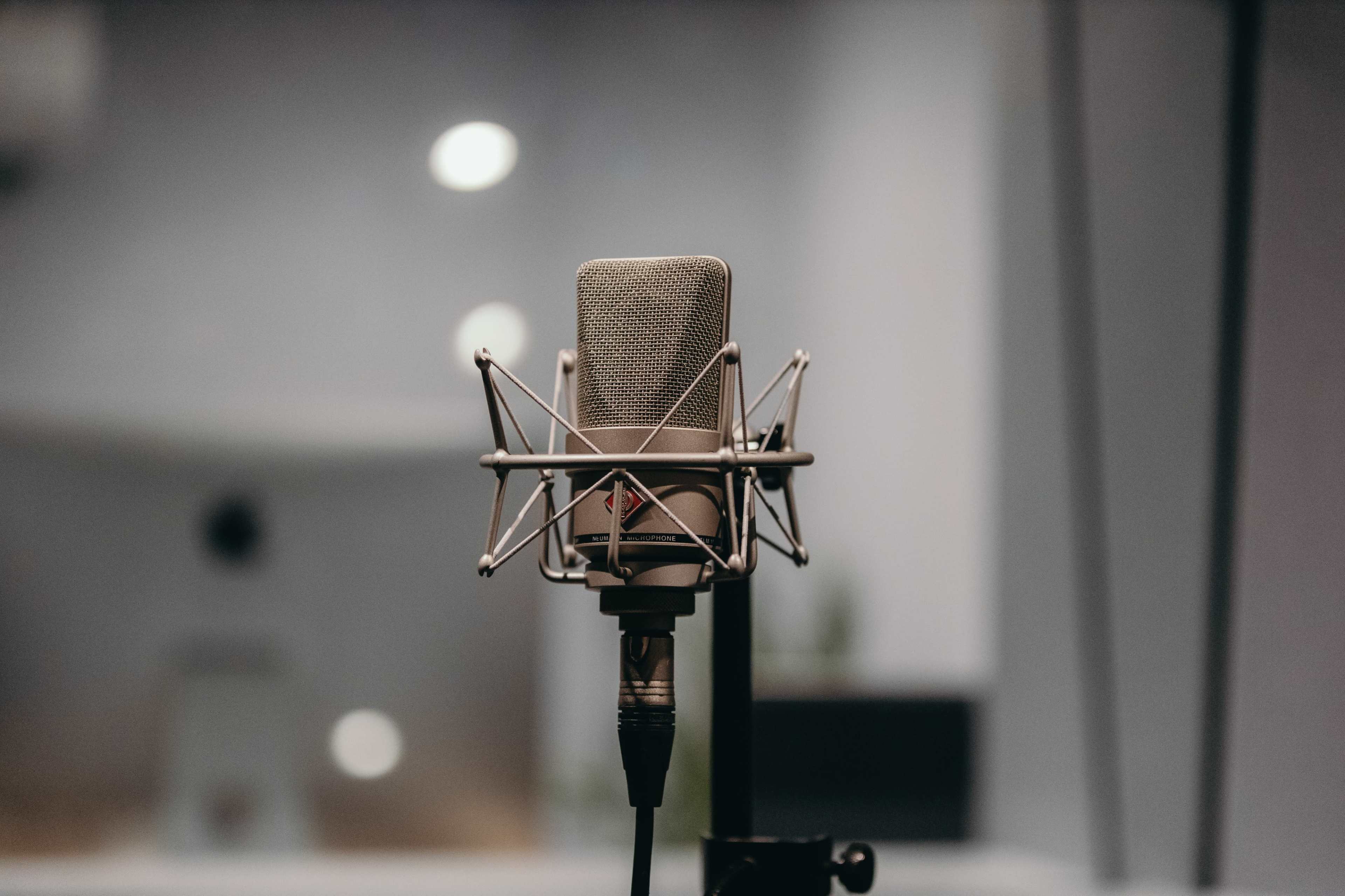 A studio microphone is mounted on a stand in a recording setting.