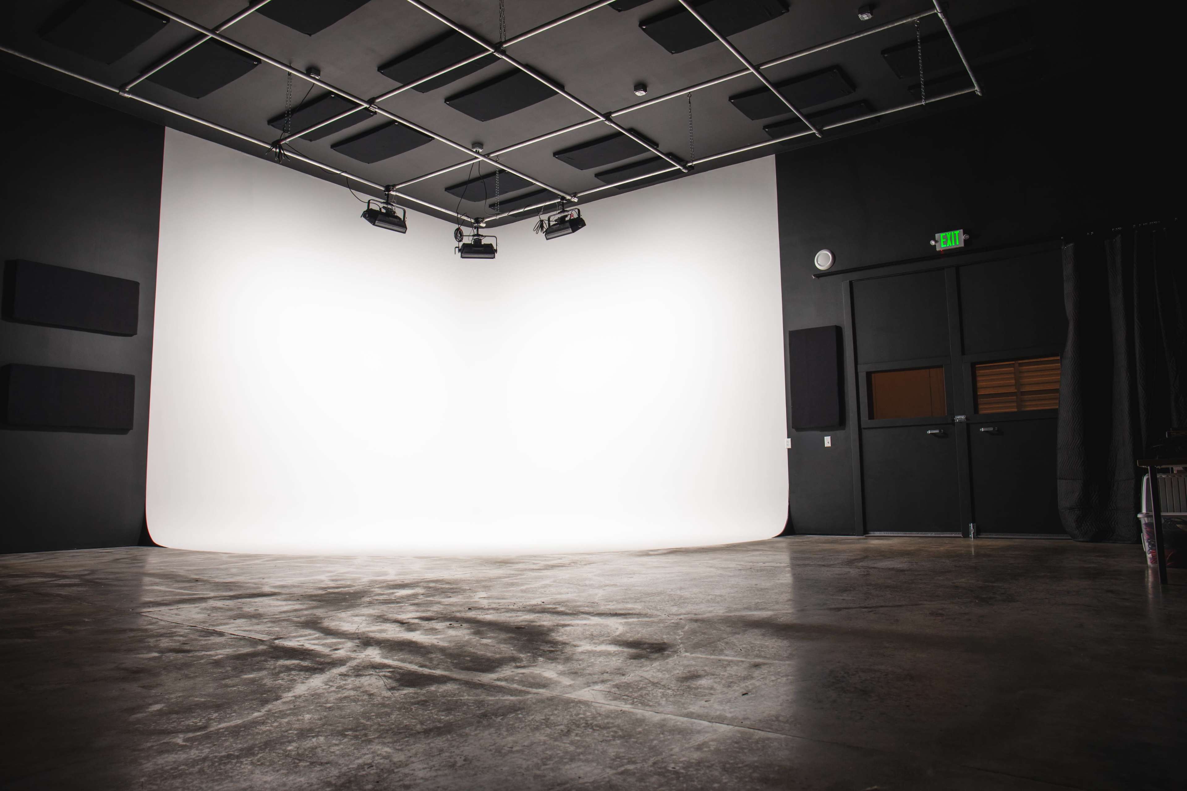 The image shows a photography studio with a seamless white backdrop and a polished concrete floor illuminated by overhead lights.