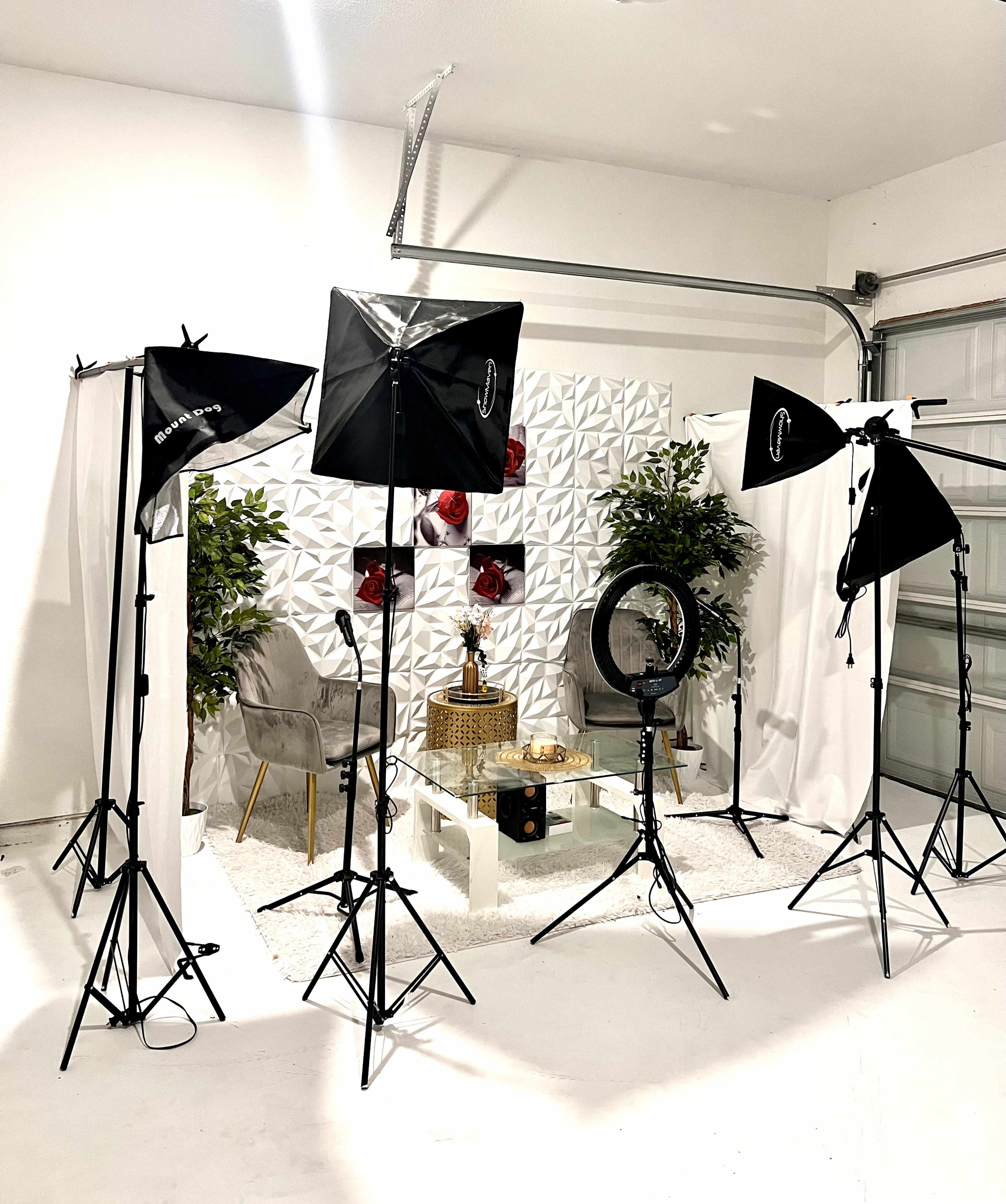 The image shows a studio setup with multiple light stands, a round mirror, and a small table decorated with a statue and greenery in a minimalist space.