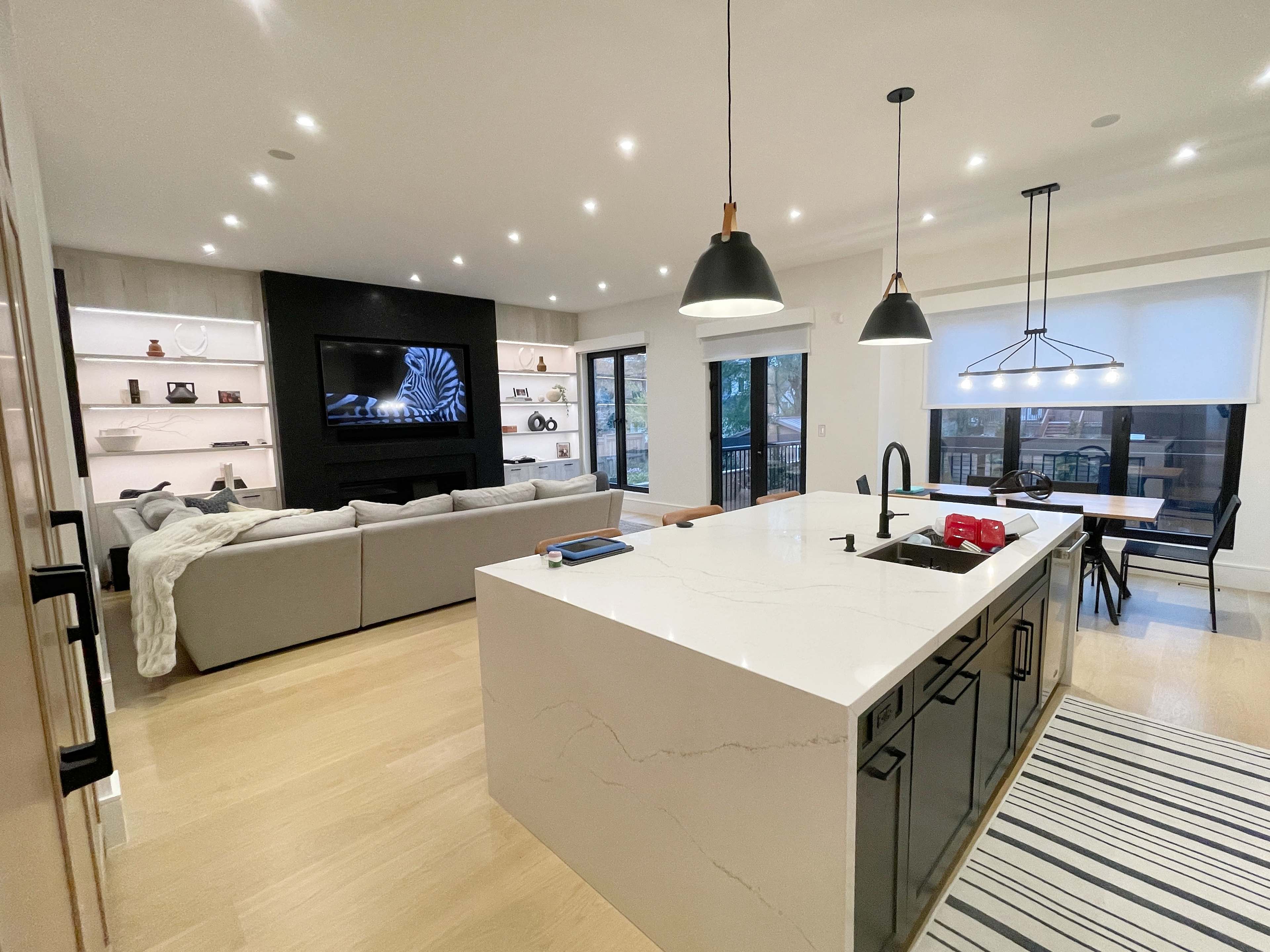 The open-concept living space features a modern kitchen with a large island, a cozy seating area, and a wall-mounted television.