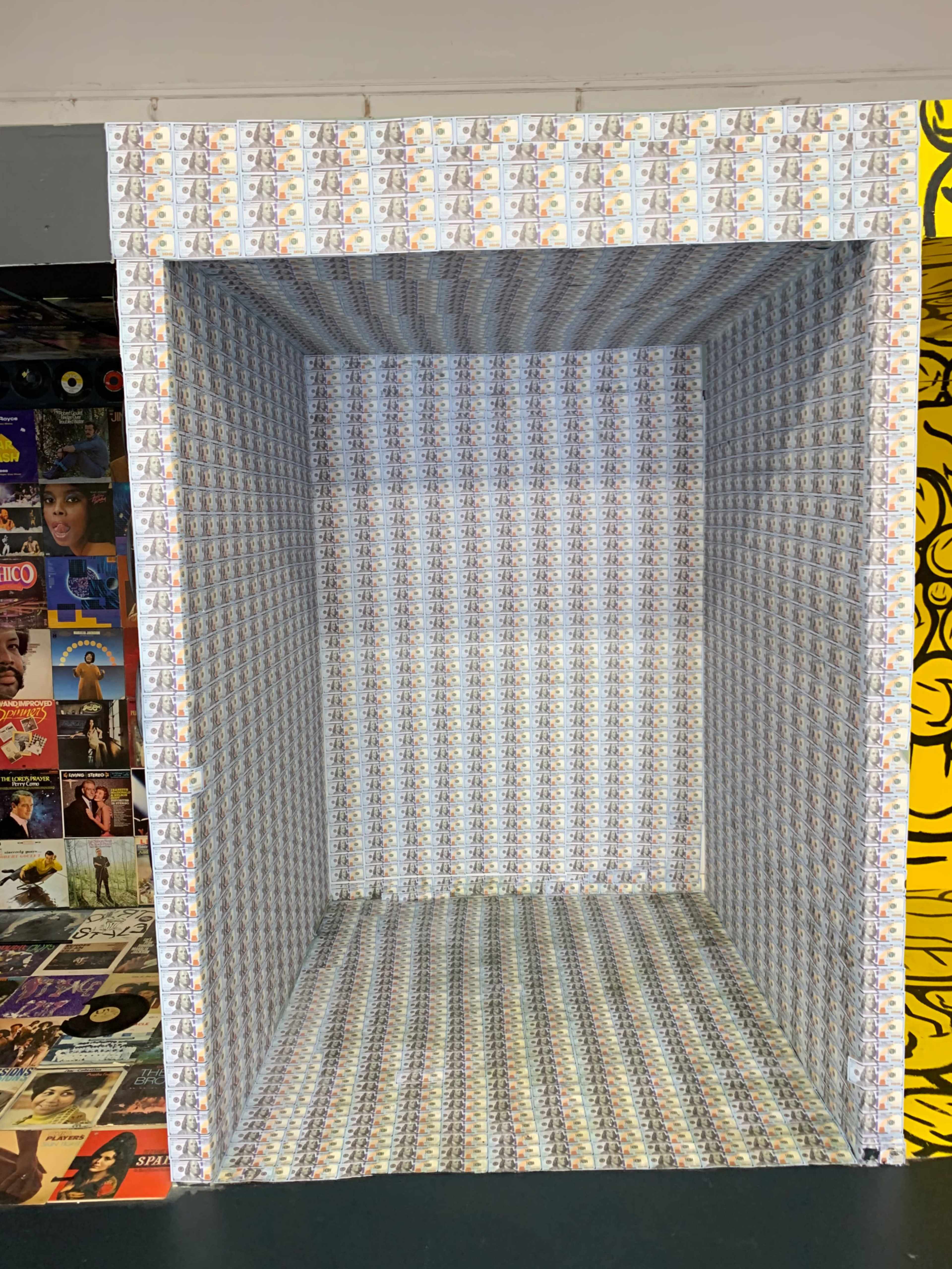 An empty cube structure with walls covered in a pattern resembling small images or designs.
