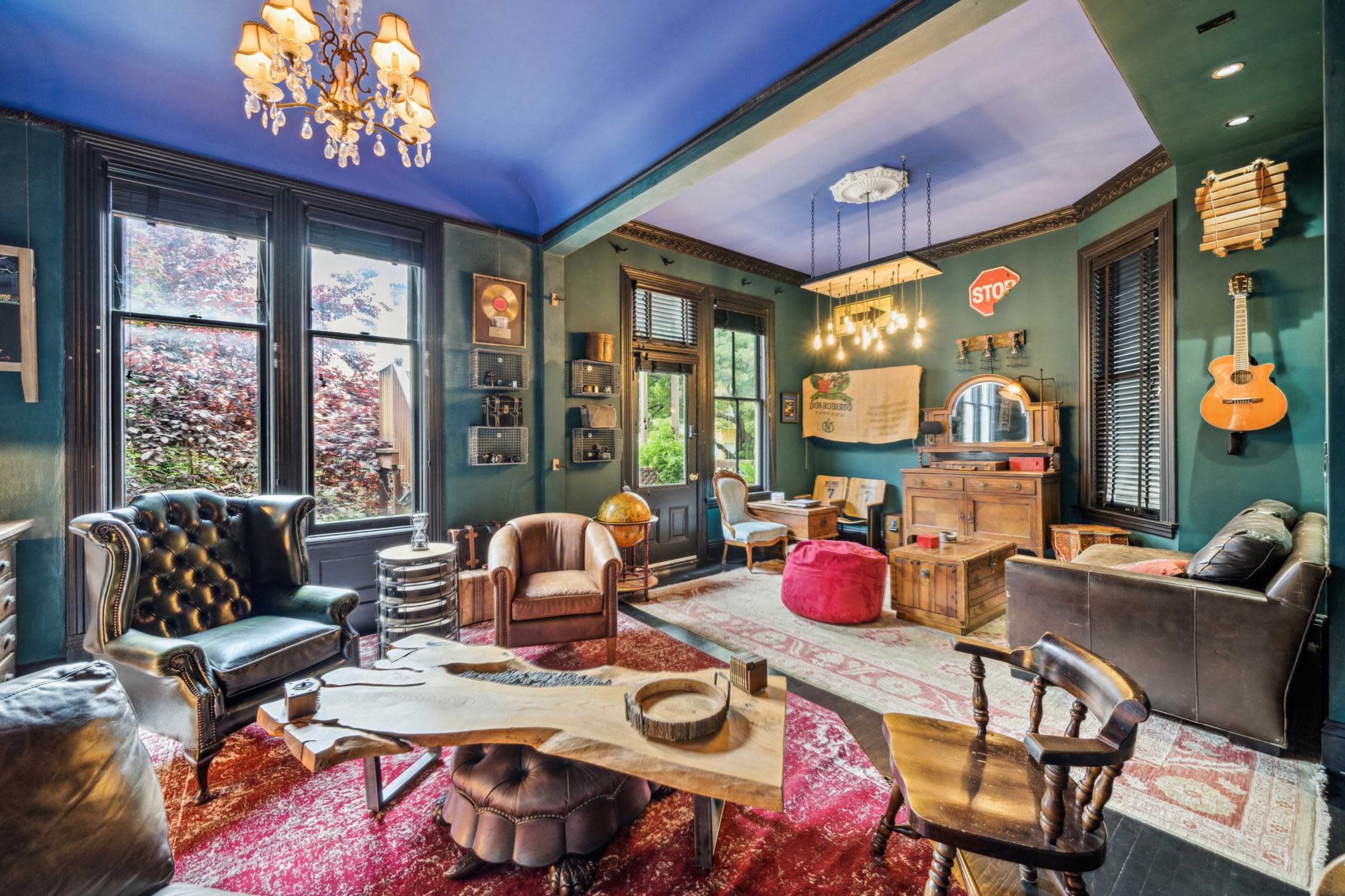 A stylish room featuring vintage furniture, a large wooden table, and eclectic decor elements, including a guitar and a "STOP" sign.
