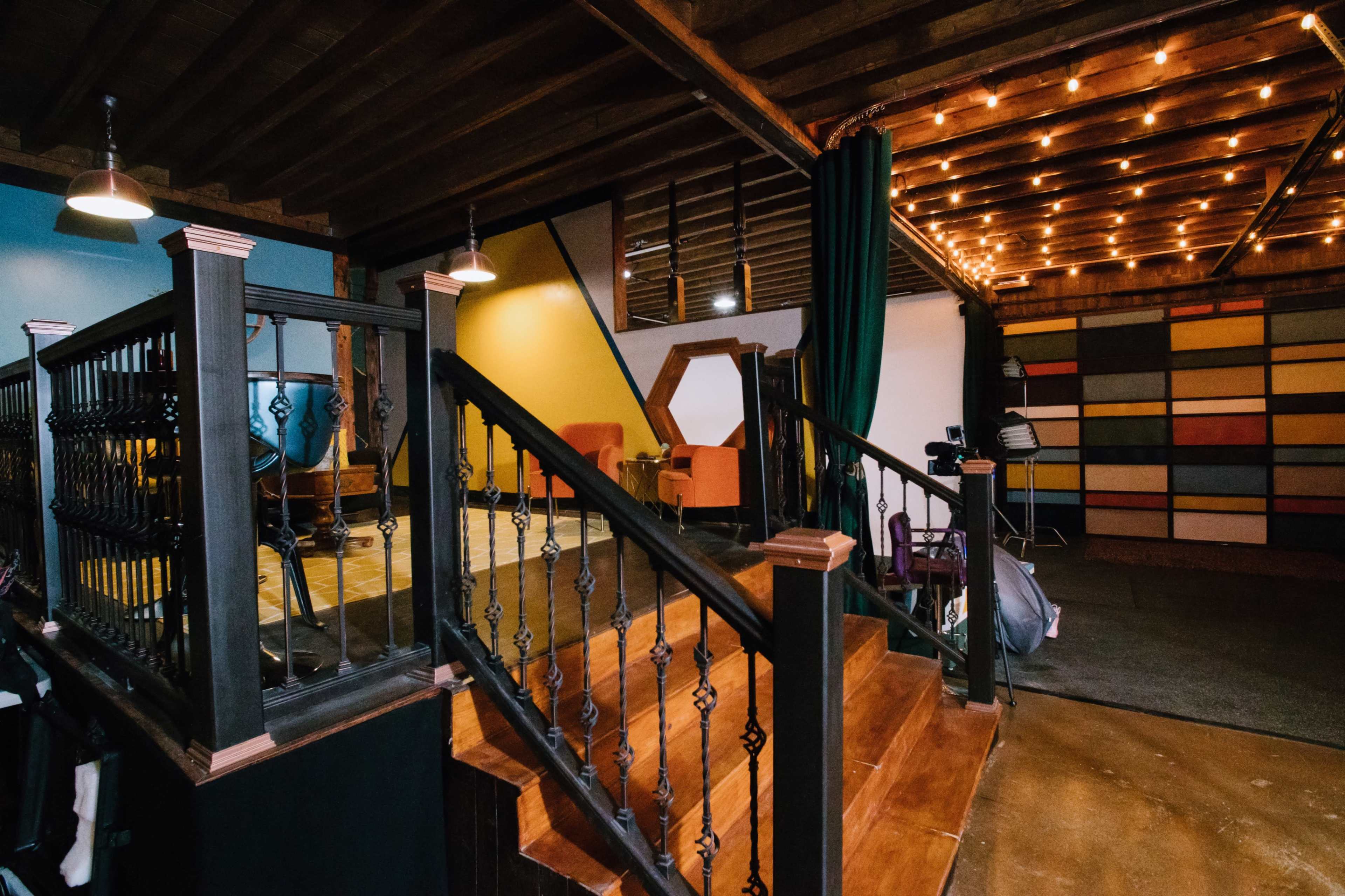 An interior space with a staircase leading to a colorful setting featuring patterned walls, seating areas, and soft lighting.