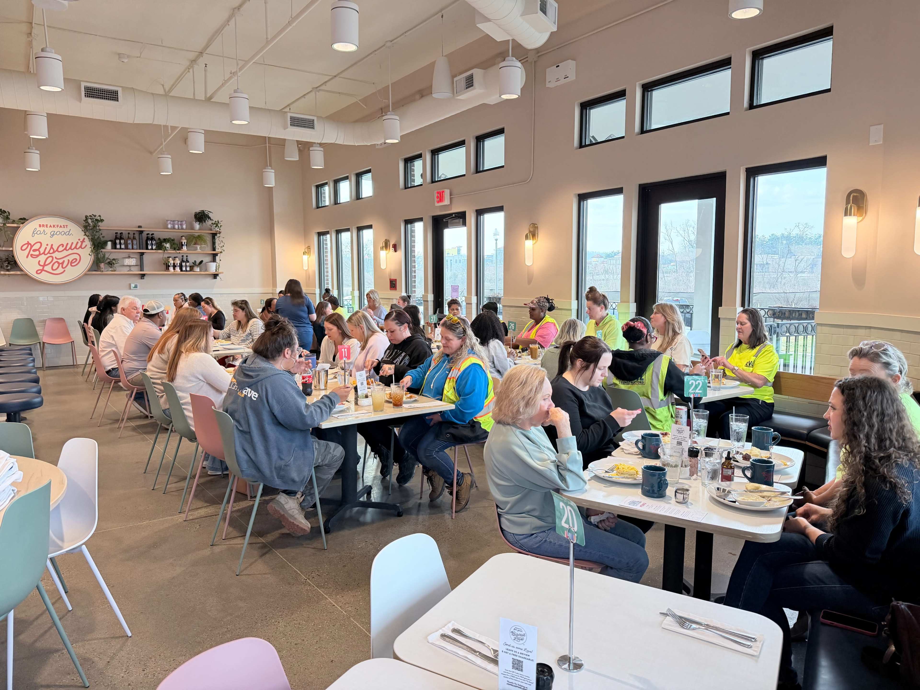 A group of people in brightly colored shirts are seated at tables in a busy restaurant, enjoying their meals and socializing.