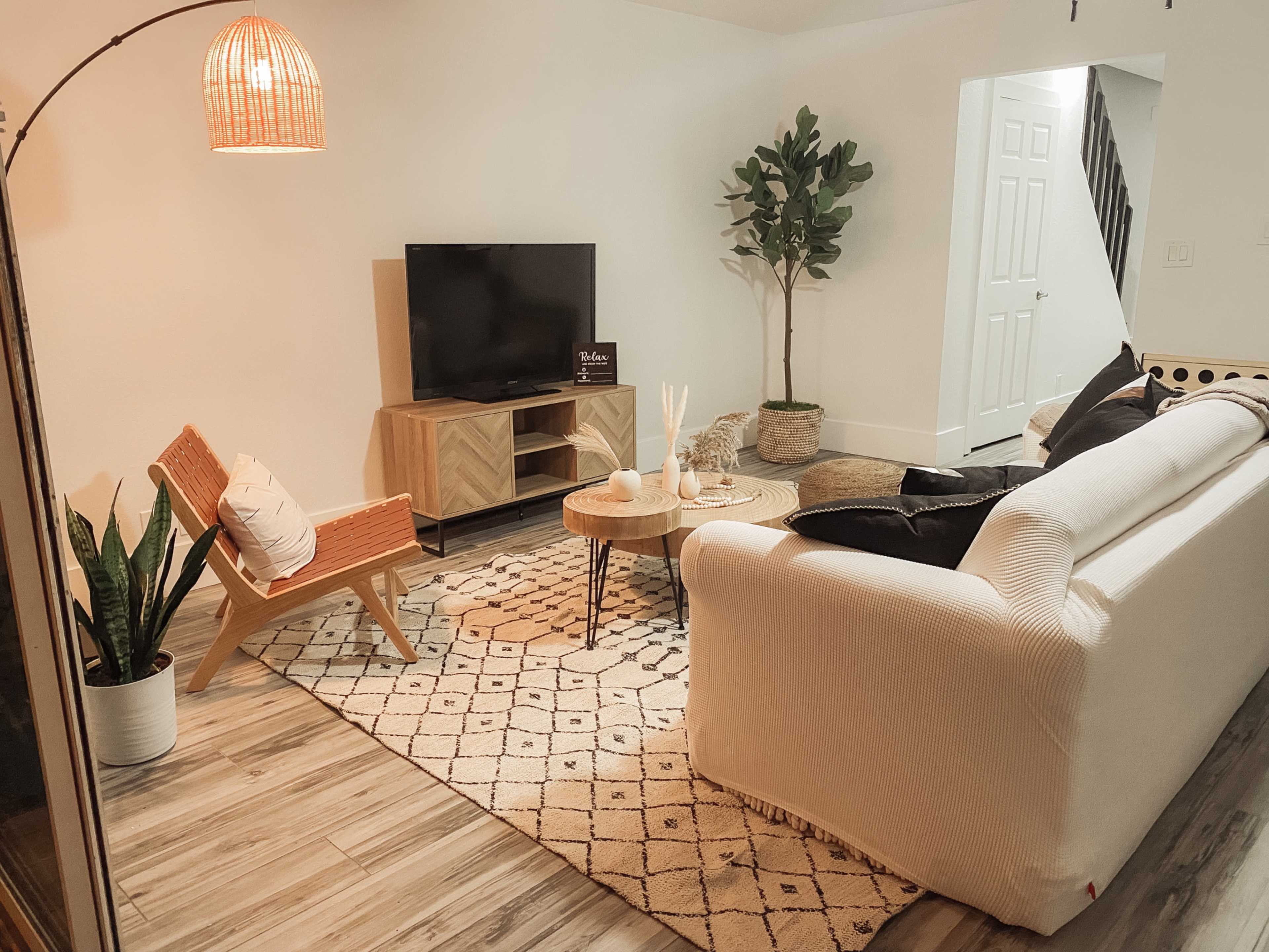 A modern living room with a plush white sofa, a cozy armchair, a wooden coffee table, and a television set against a light-colored wall.