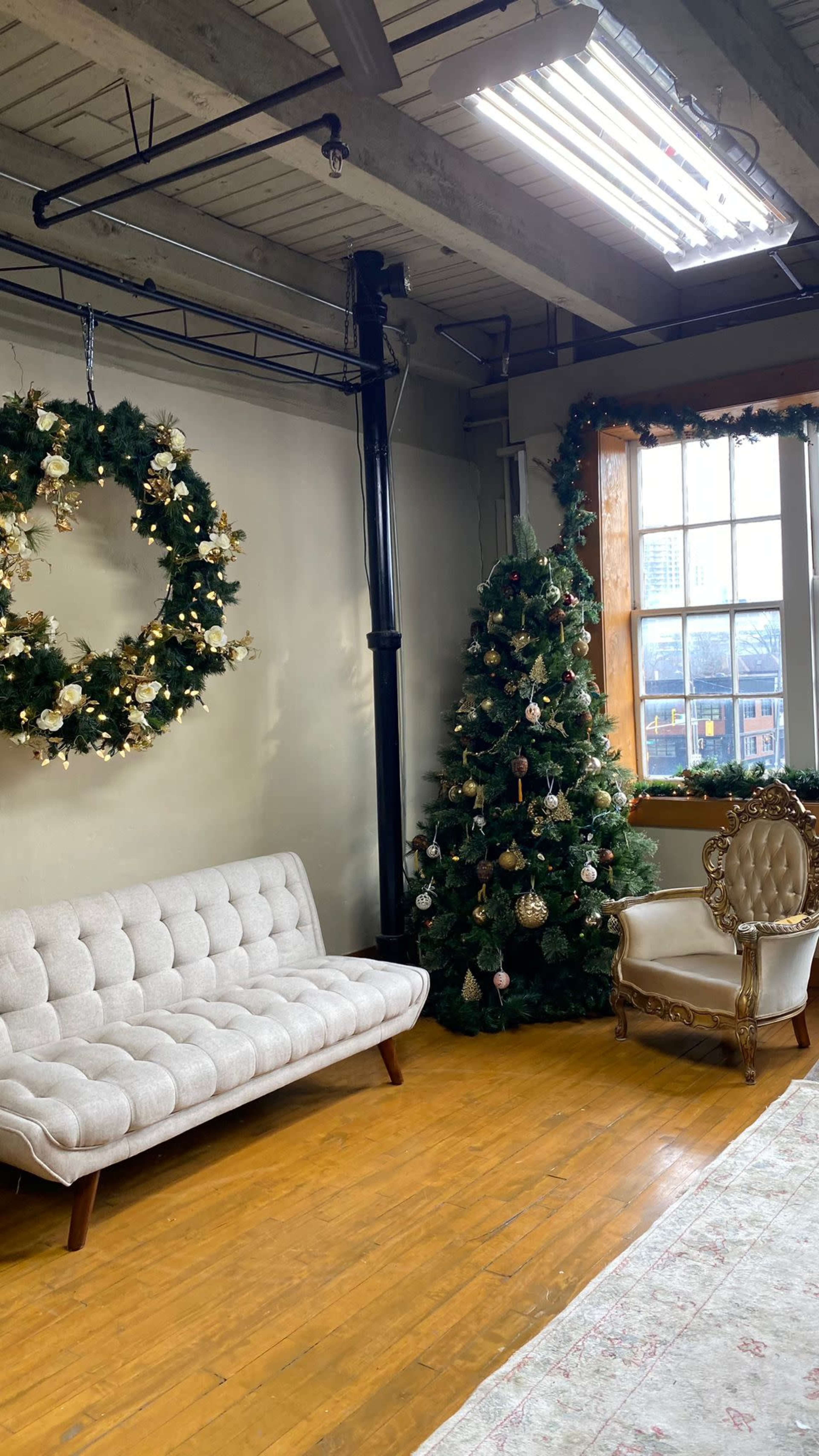 The scene features a decorated living space with a Christmas tree and wreaths, alongside a tufted sofa and a vintage armchair on a wooden floor.