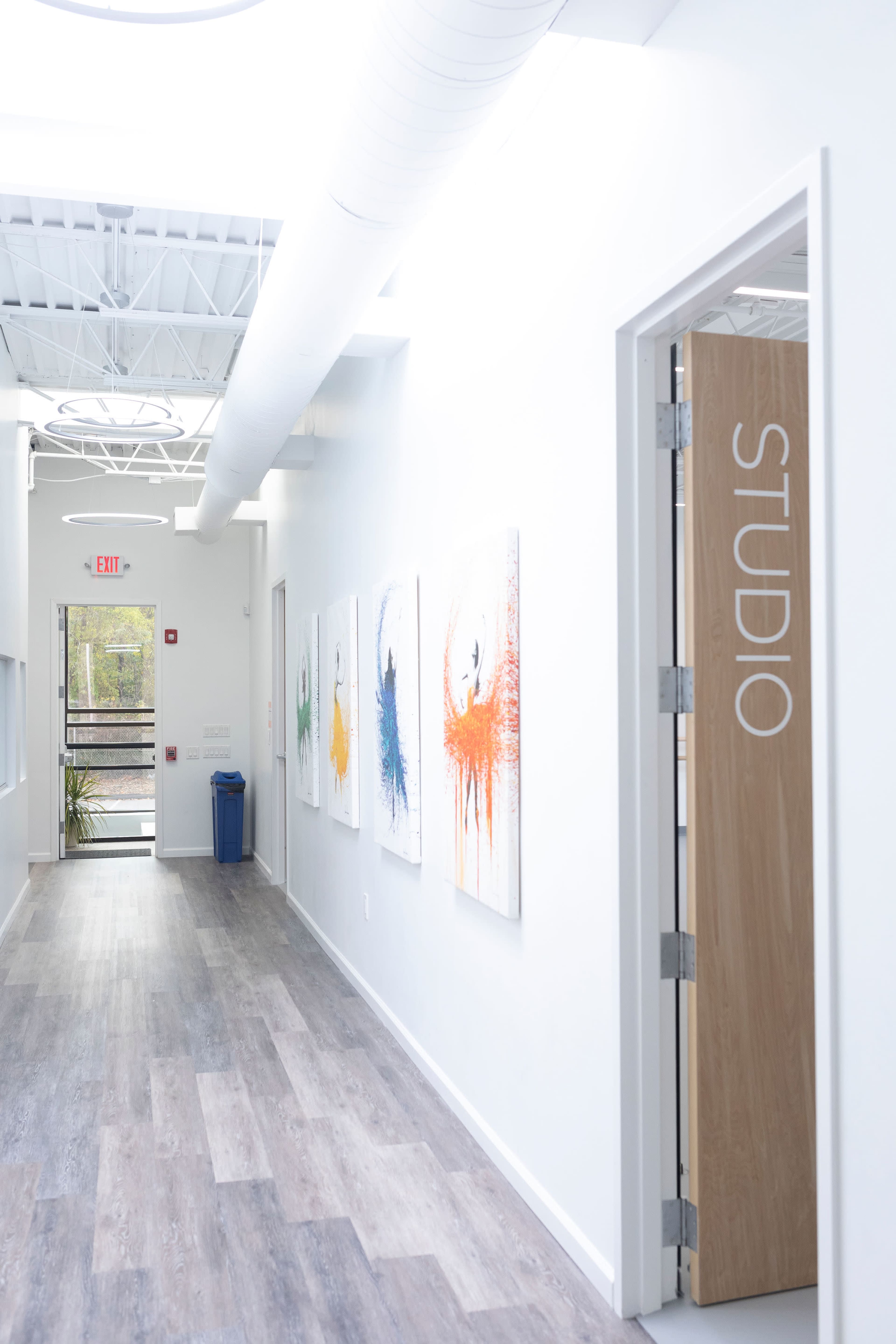 A hallway features a wooden door labeled "STUDIO" and several paintings with colorful splashes on the walls.