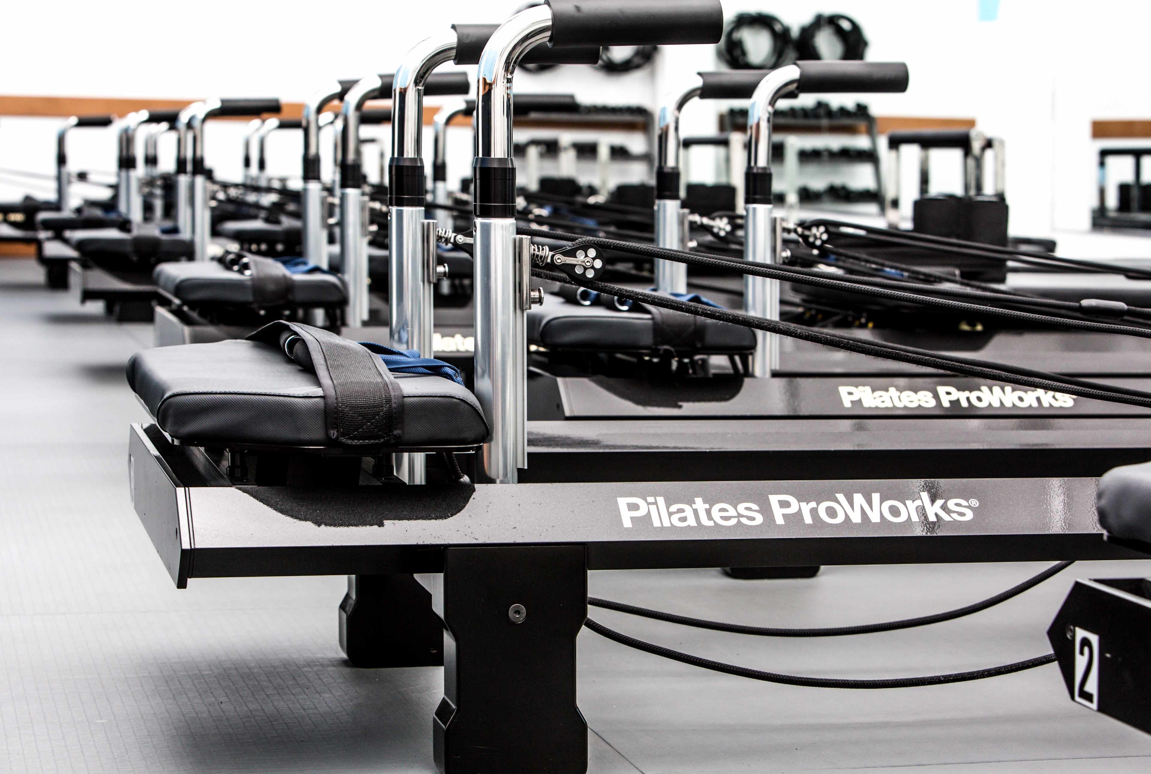 A row of Pilates reformers arranged neatly in a fitness studio.