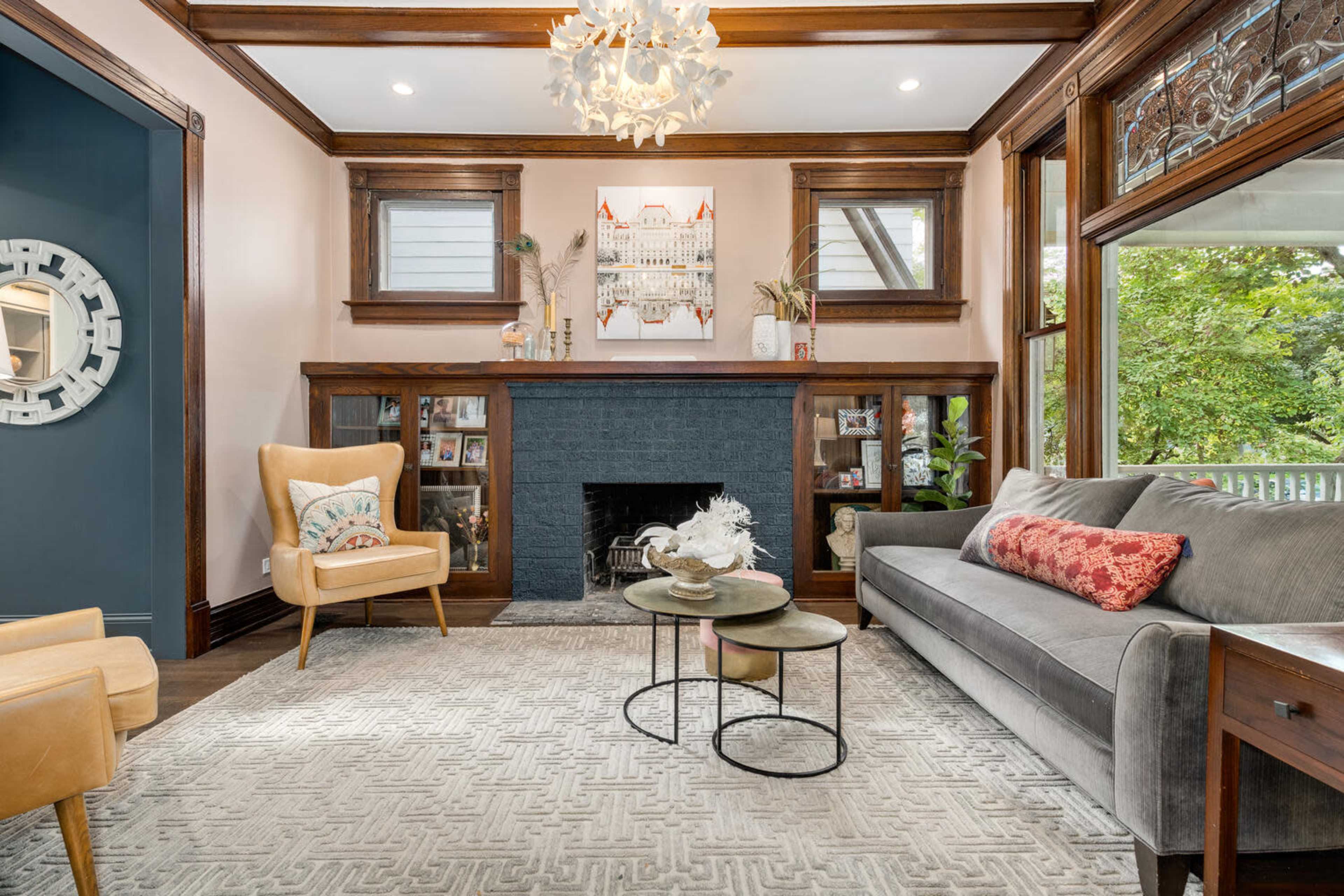 A stylish living room featuring a gray sofa, two chairs, a small coffee table, and a decorative fireplace.