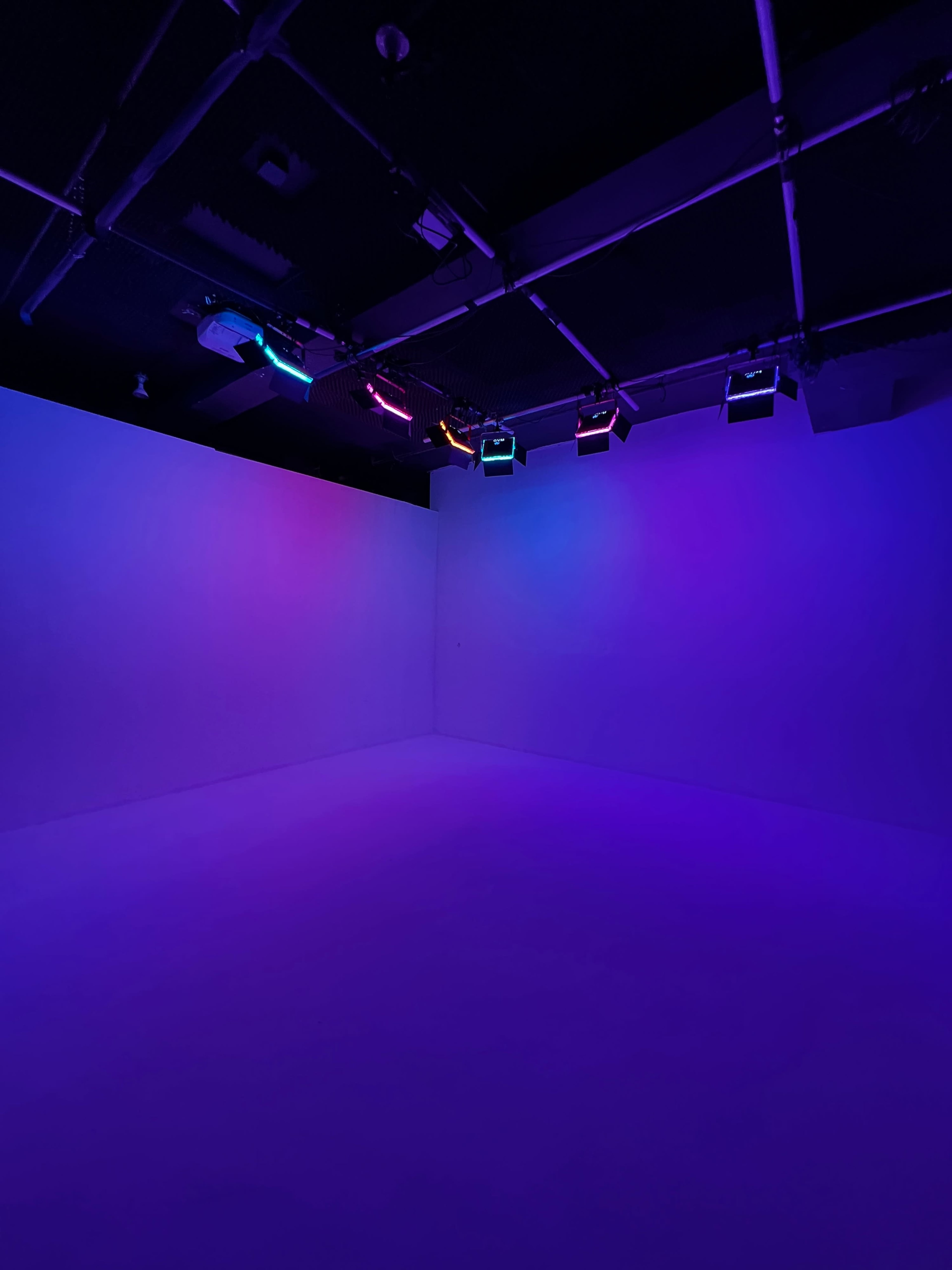An empty room with purple and blue lighting from overhead fixtures.