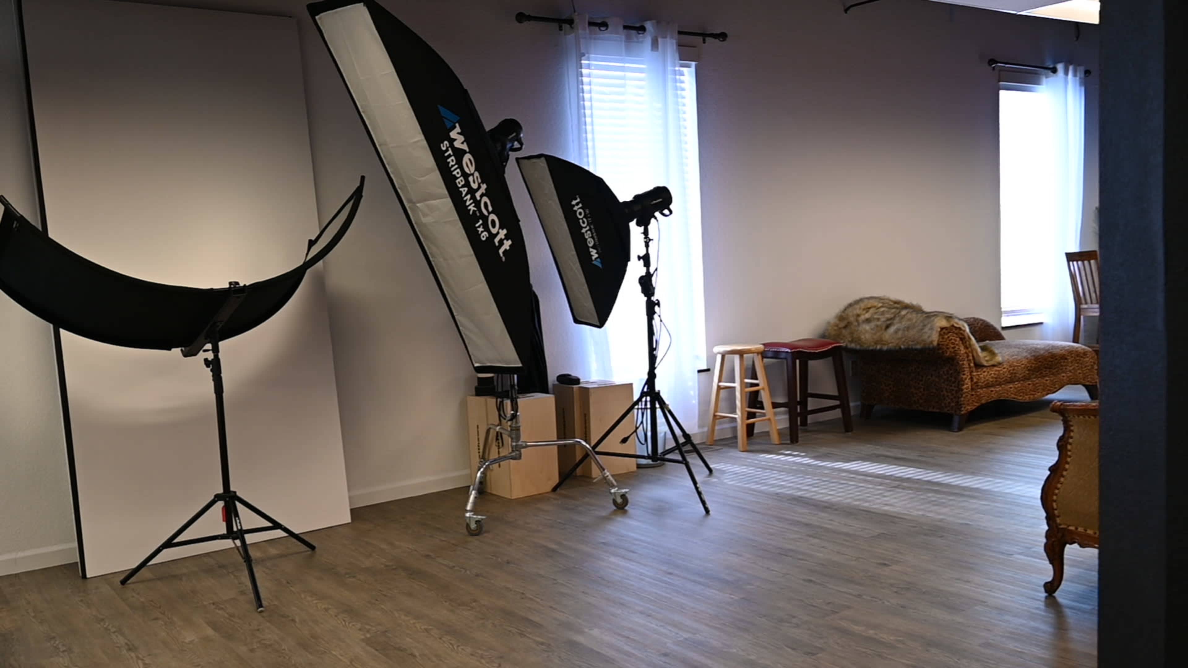 A photography studio with lighting equipment, a backdrop, and a brown upholstered couch.
