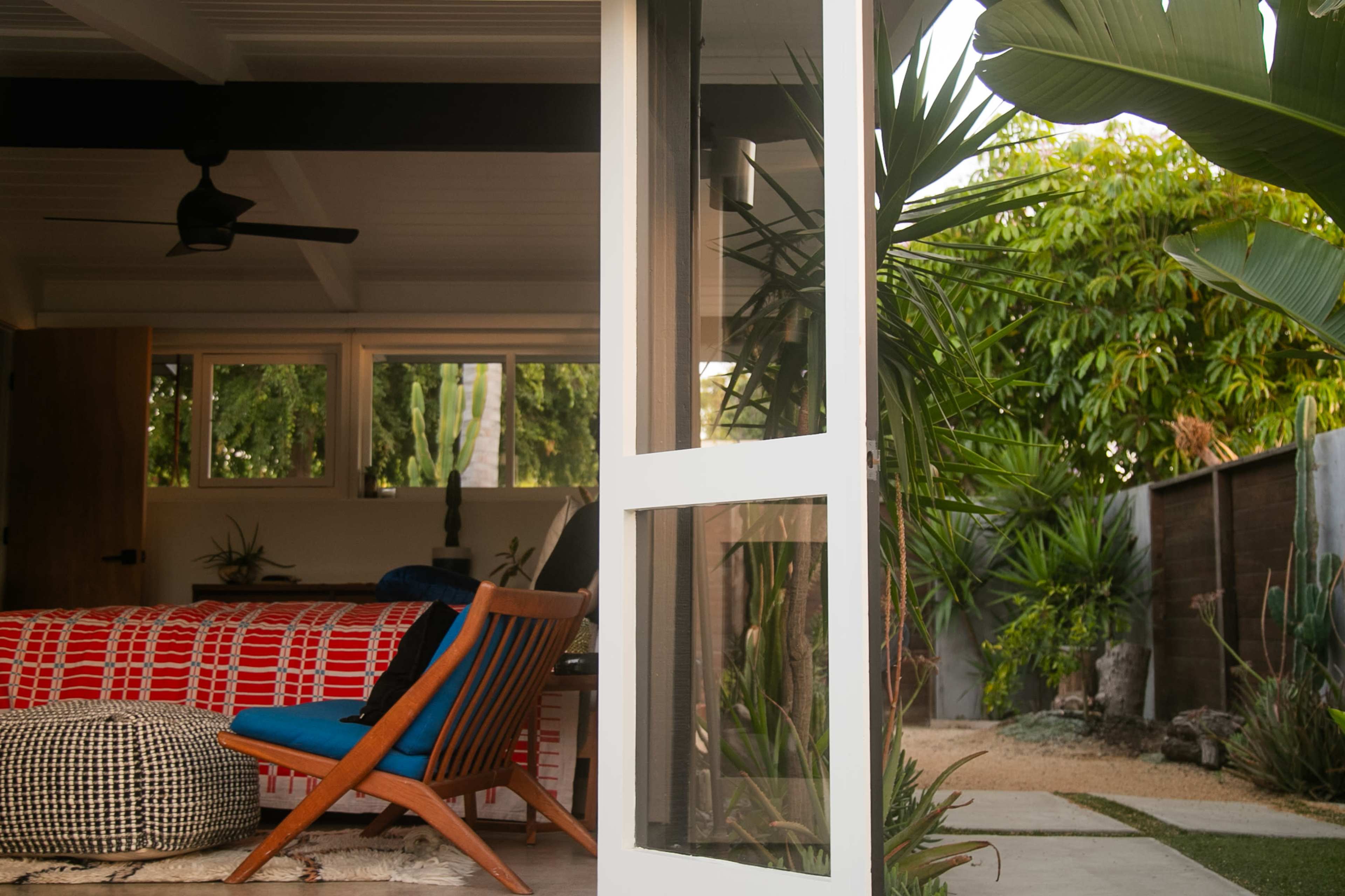 A modern living space with an open door leading to a landscaped garden featuring tropical plants.