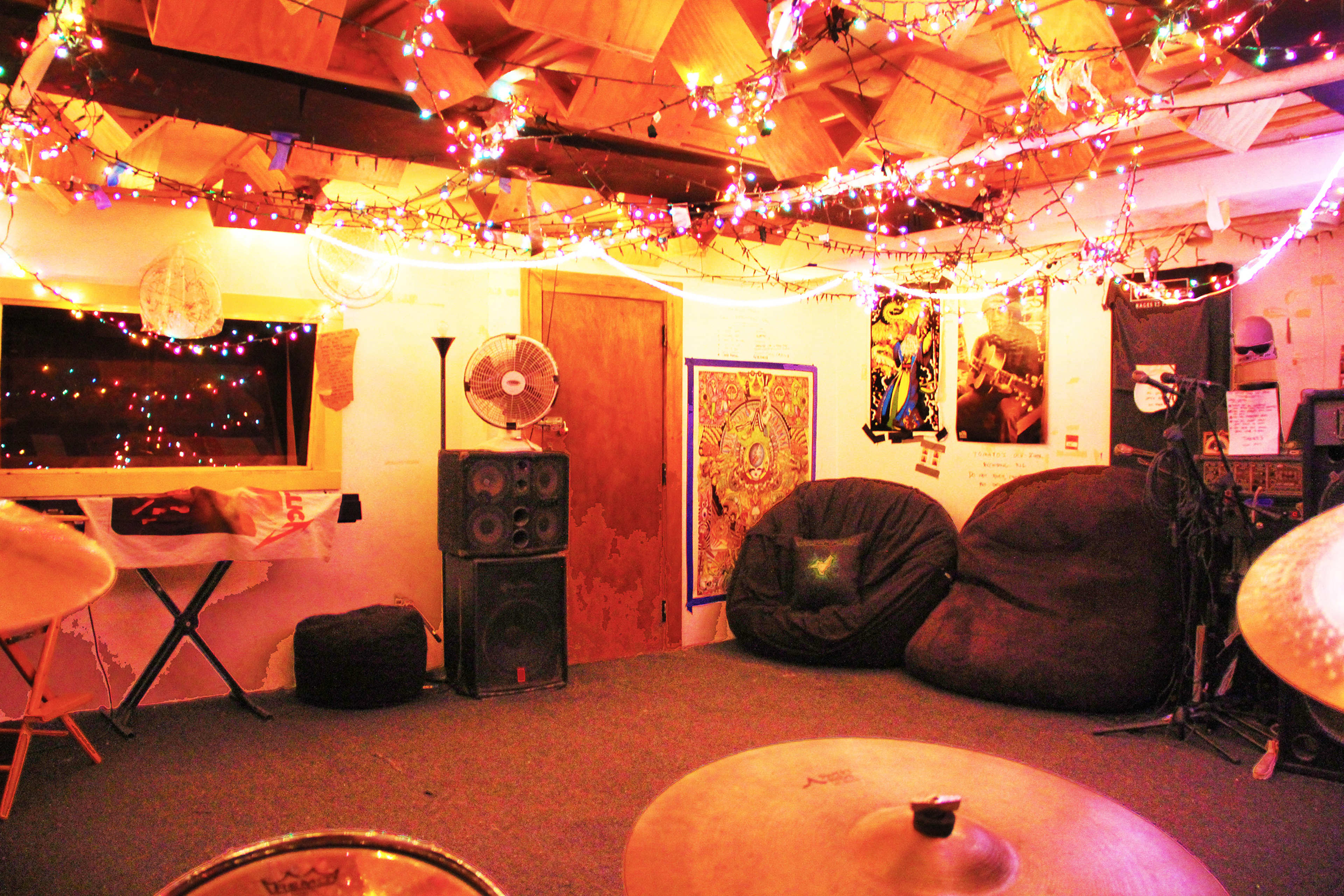 A decorated music practice room with colorful string lights, bean bag chairs, and musical equipment.