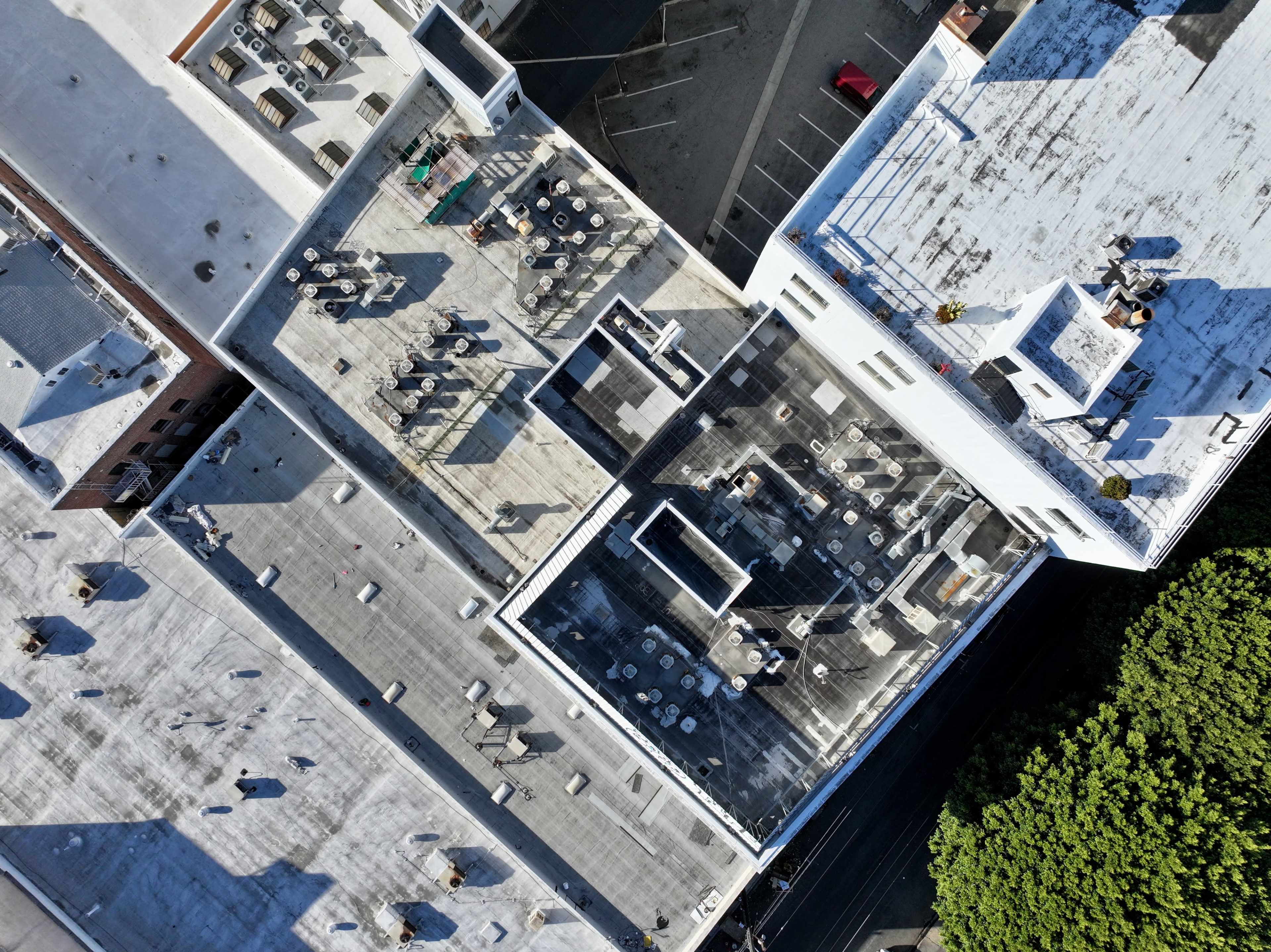 An aerial view of several rooftops with tables and chairs arranged on their surfaces.