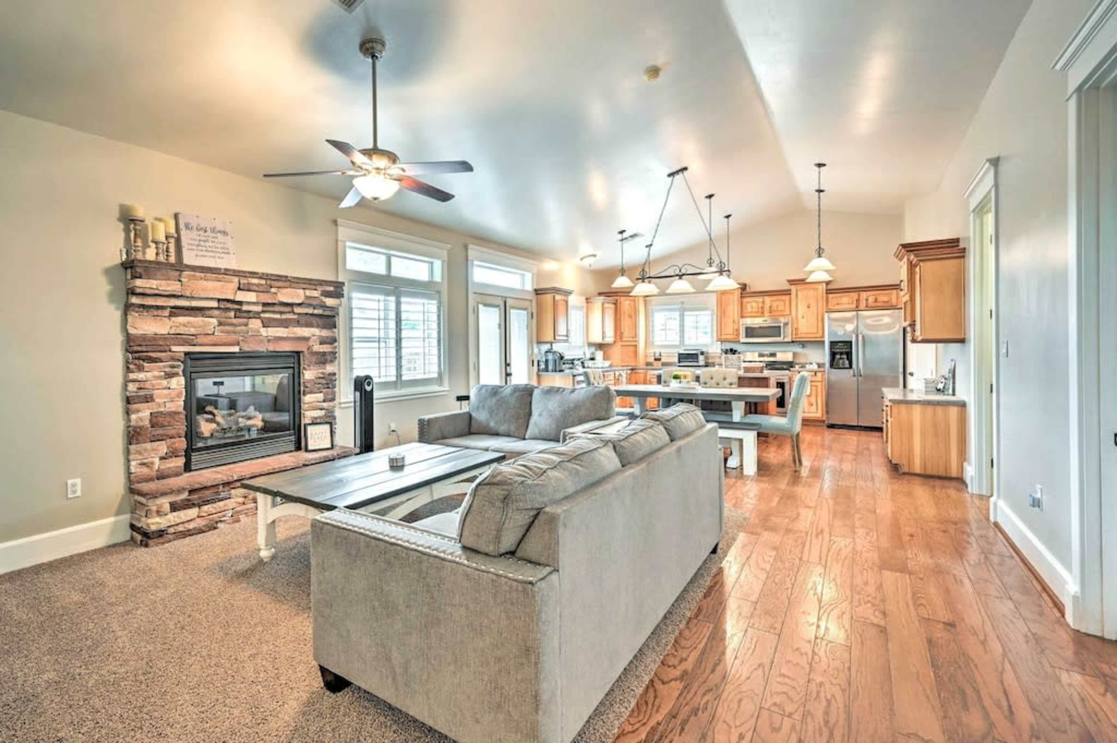 A spacious, open-concept living area with a comfortable sofa, a dining table, and a kitchen featuring wooden cabinets and a stone fireplace.