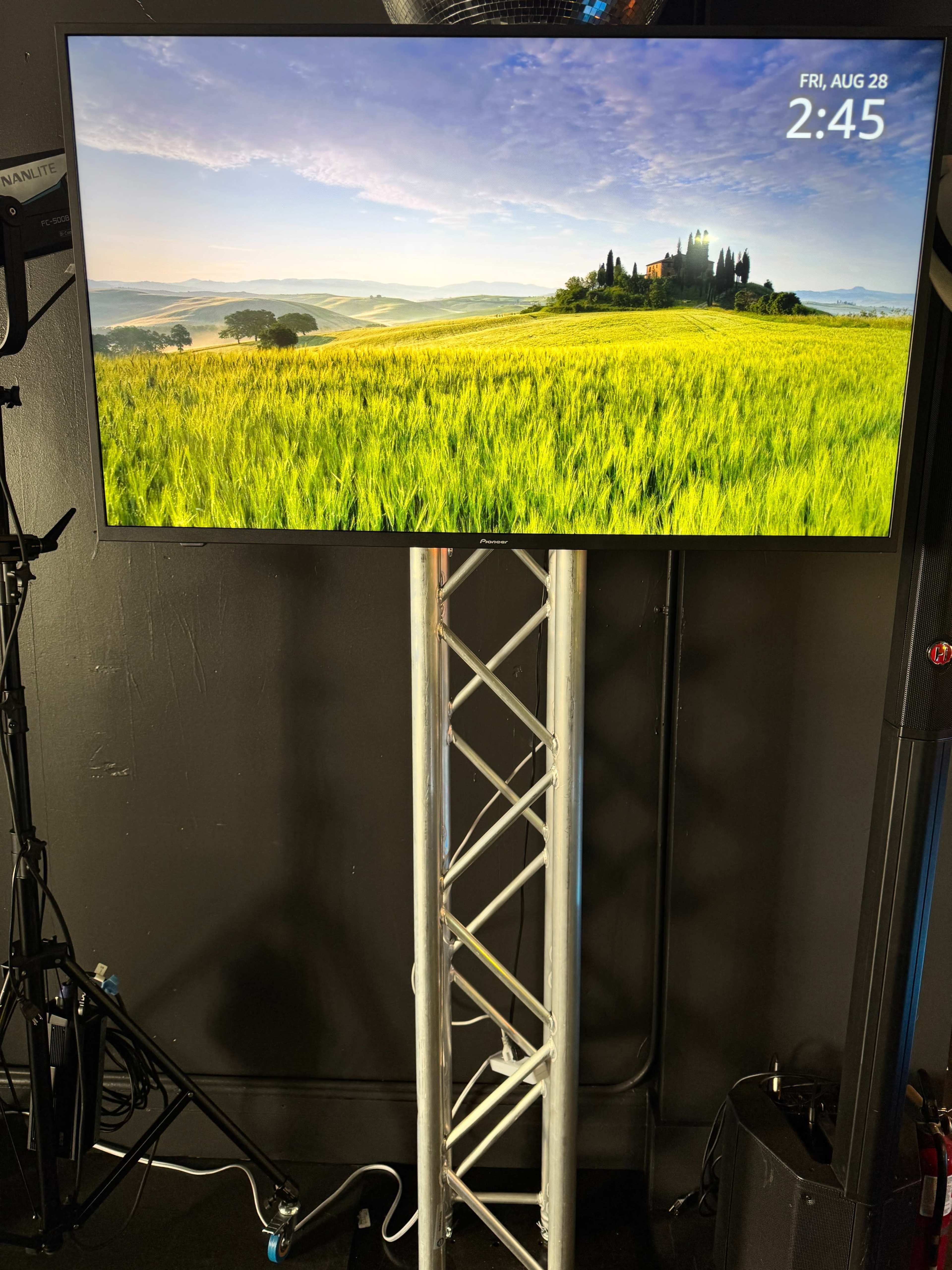 A large television displays a scenic image of a green field and a distant castle under a blue sky.