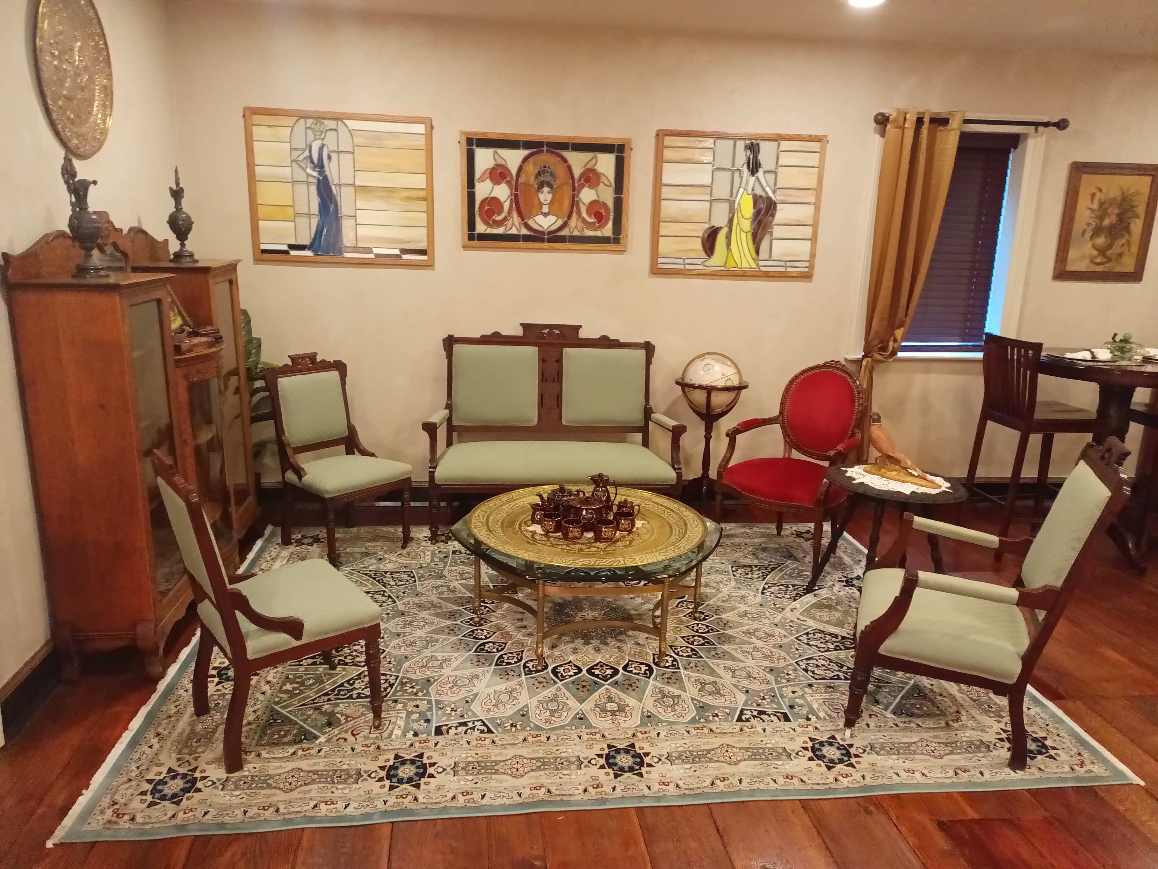 A vintage-style sitting room furnished with a round table, several chairs, and decorative artwork on the walls.
