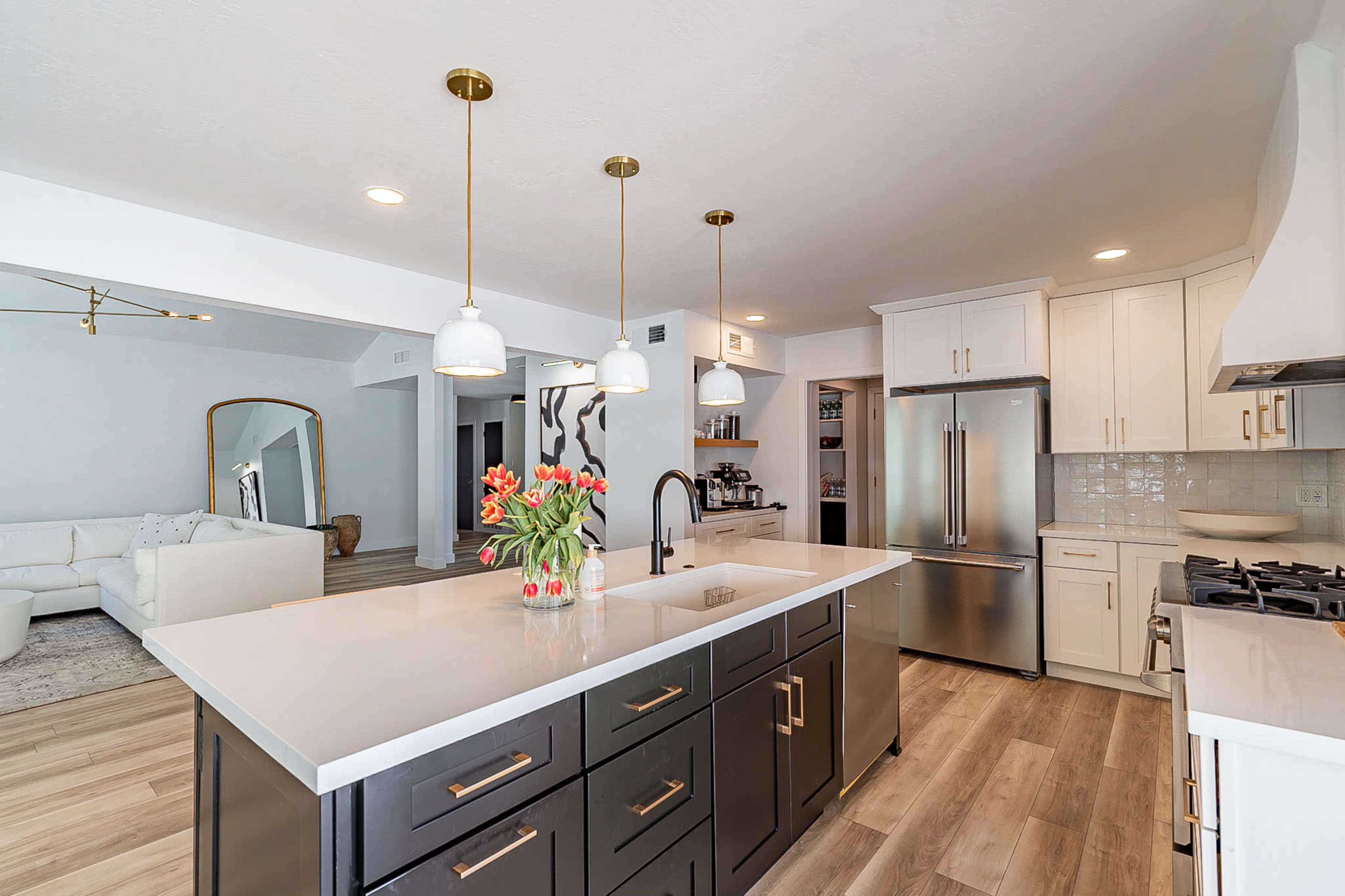 A modern kitchen with a large island featuring a sink, pendant lights overhead, and stainless steel appliances.