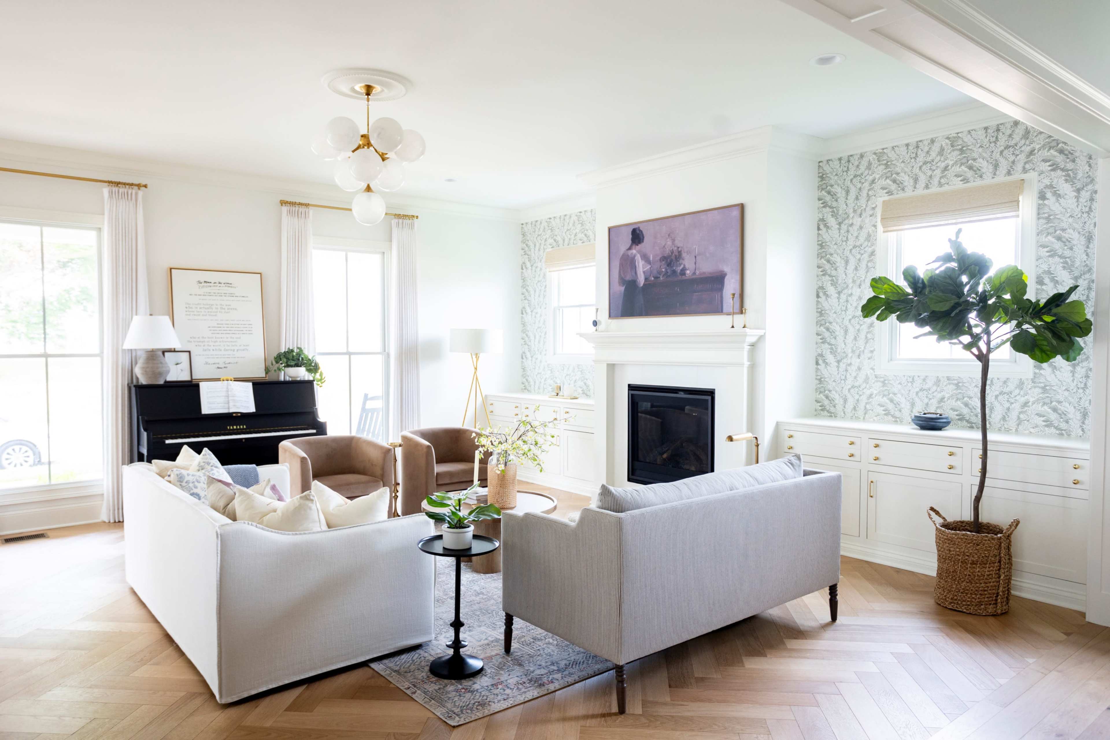A modern living room features a white sofa, two brown chairs, a black piano, and a decorative plant, all arranged around a fireplace against a patterned wall.