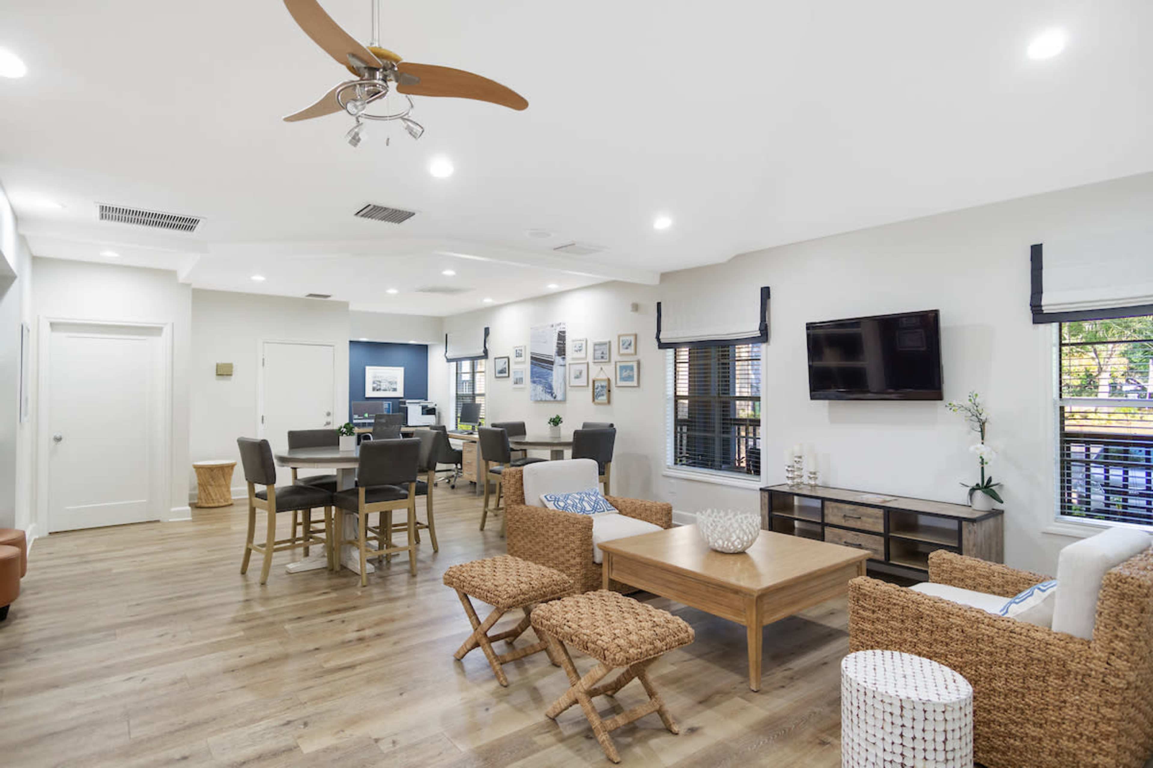 A modern living area with a central seating arrangement, a dining table, and a flat-screen TV mounted on the wall.