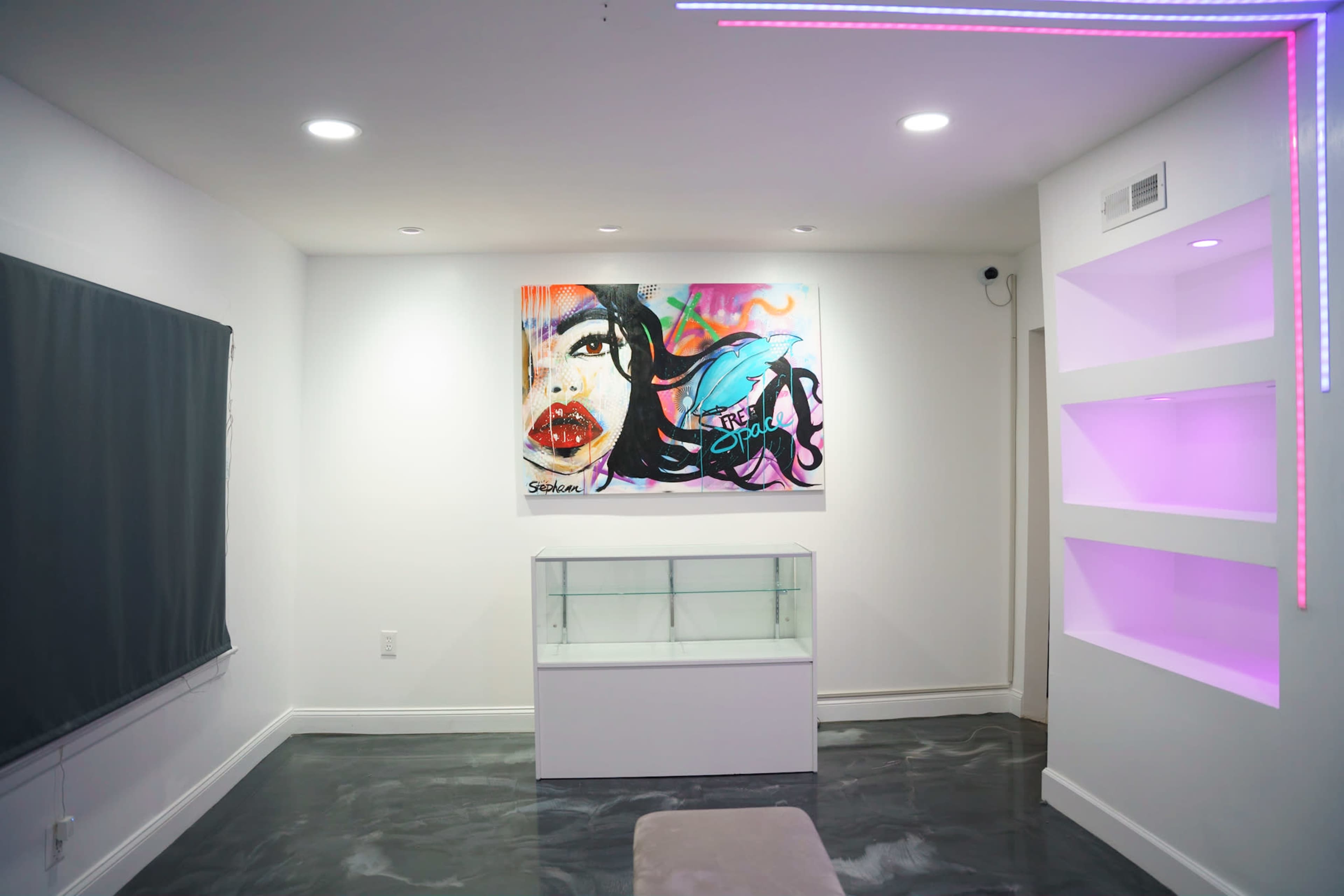 A modern interior space featuring a colorful mural on the wall, a glass display case, and LED lighting accents.