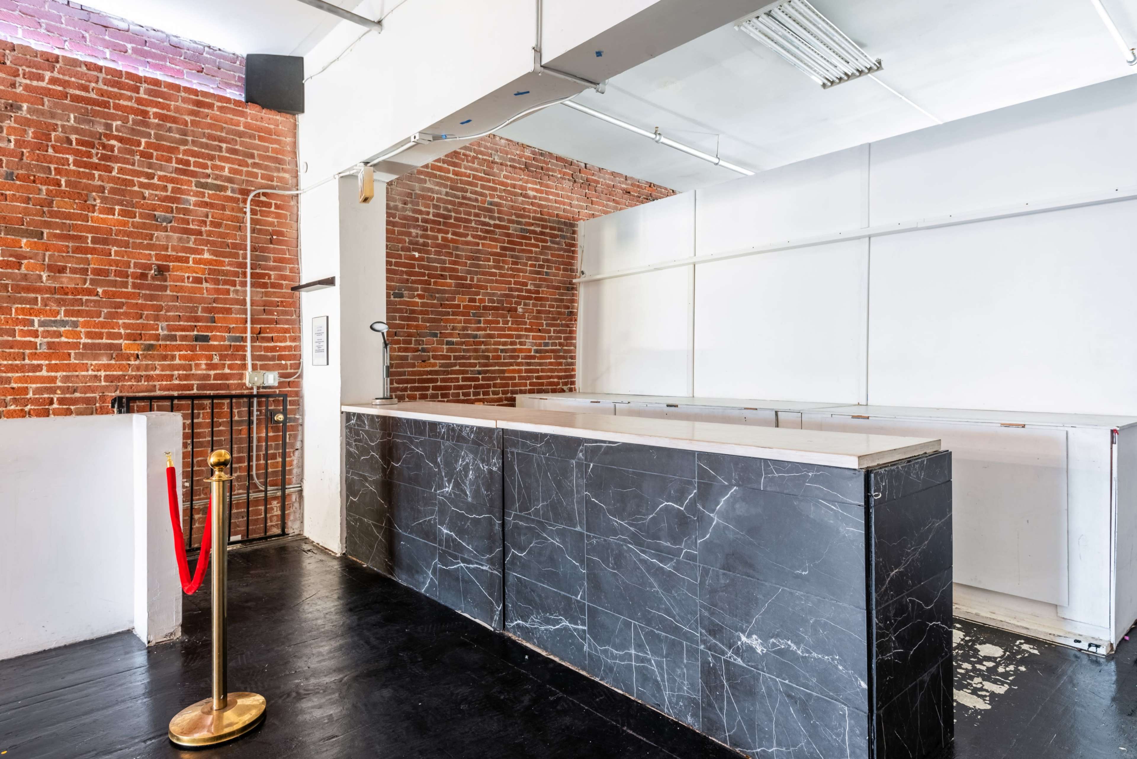 The image shows an empty reception area featuring a marble counter and exposed brick walls.