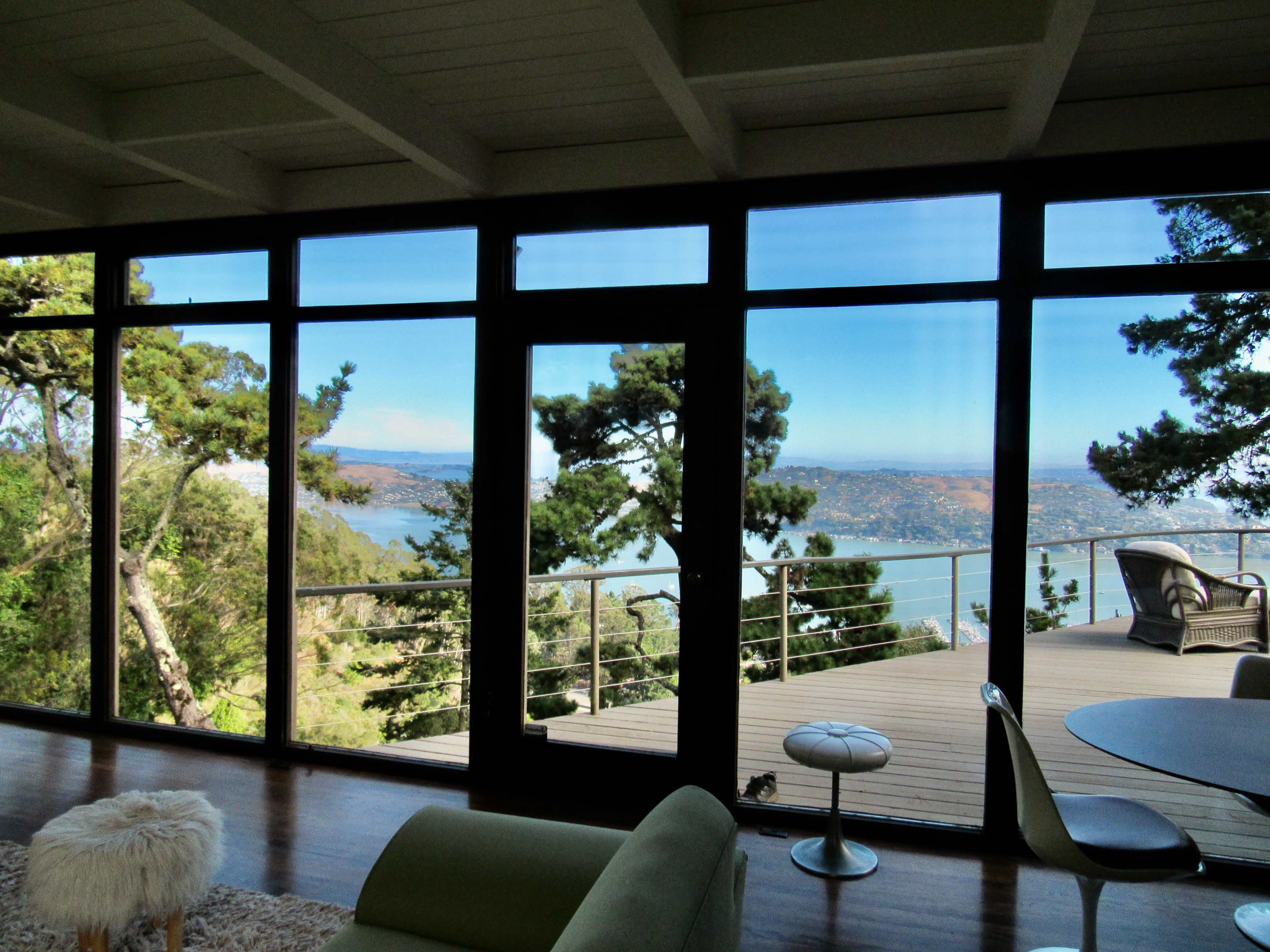 A modern living area with large glass windows overlooking a scenic landscape of trees and a body of water.