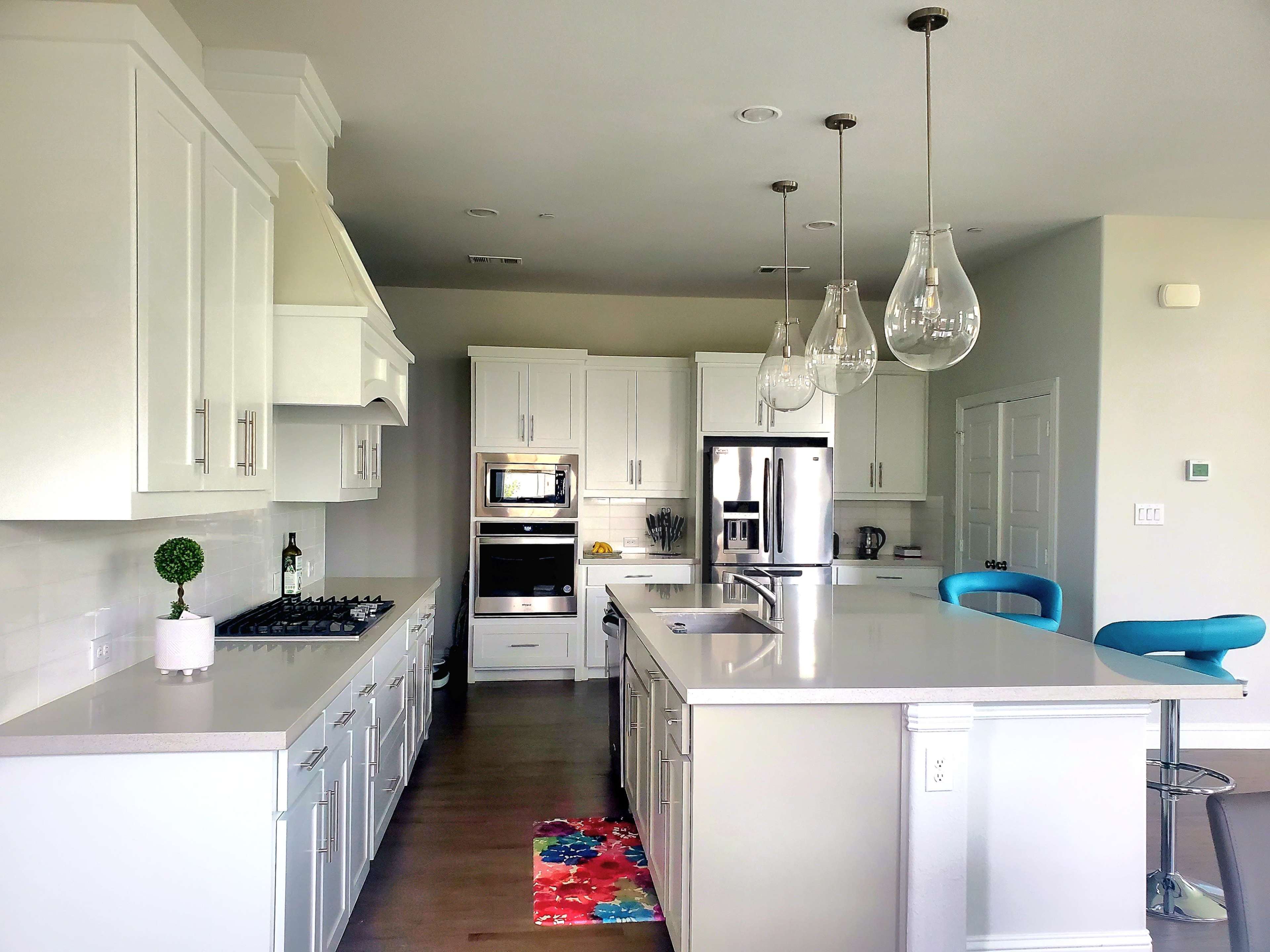 A modern kitchen featuring white cabinetry, stainless steel appliances, and a central island with bar stools.