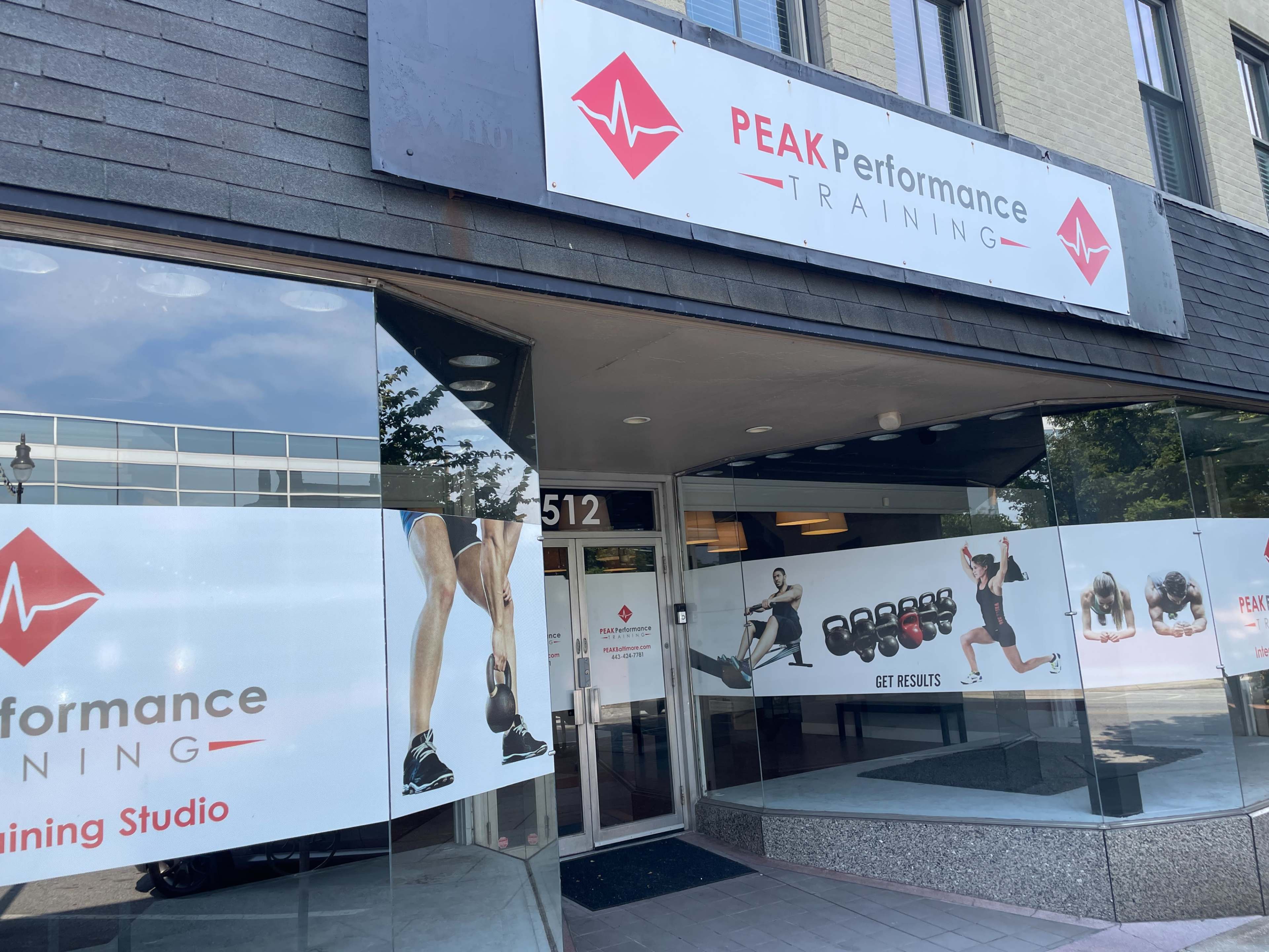 The storefront of Peak Performance Training, featuring large windows with promotional graphics showcasing fitness activities and a sign above the entrance.