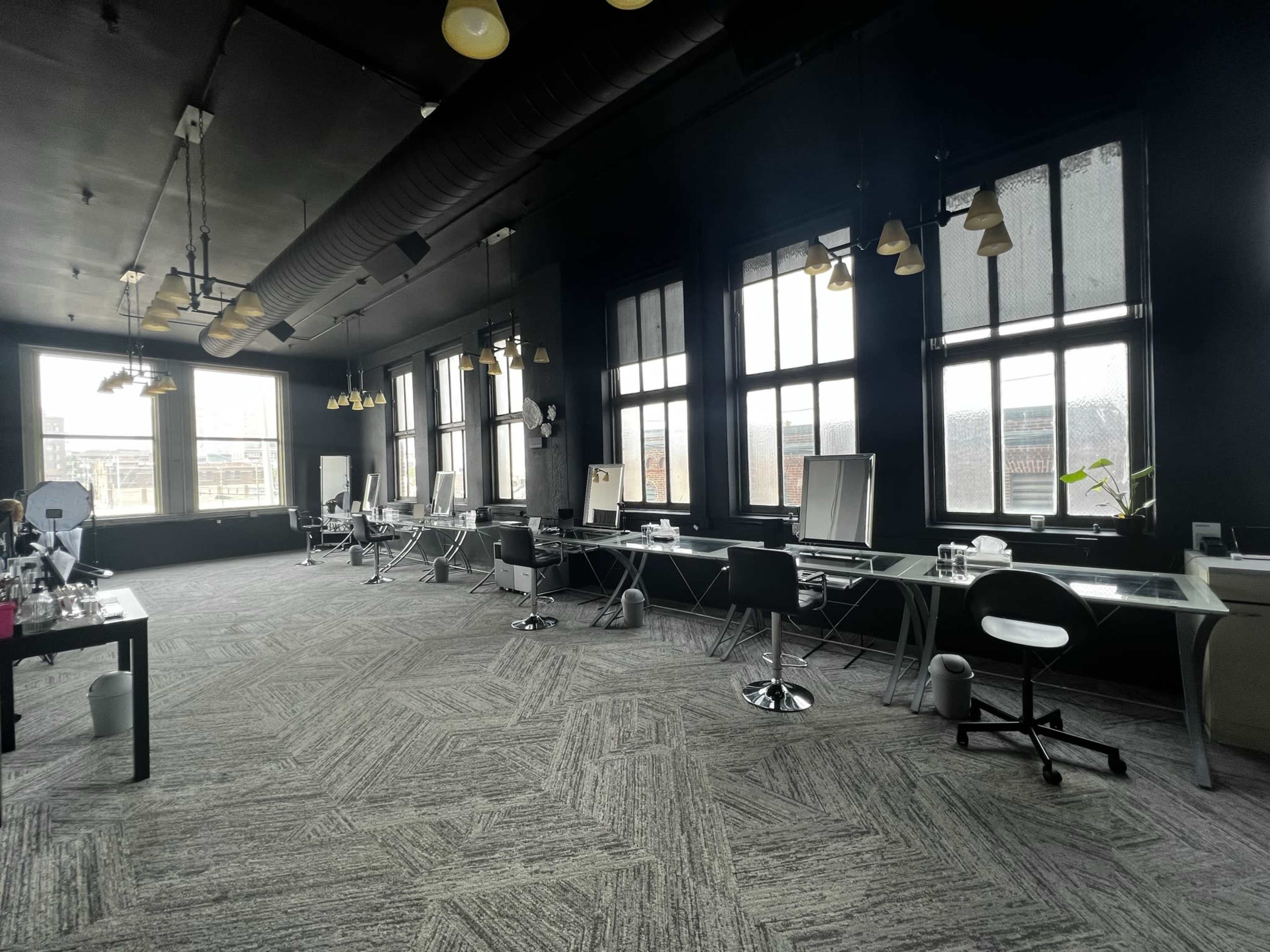 A spacious, modern office interior with large windows, multiple workstations, and a minimalist design.