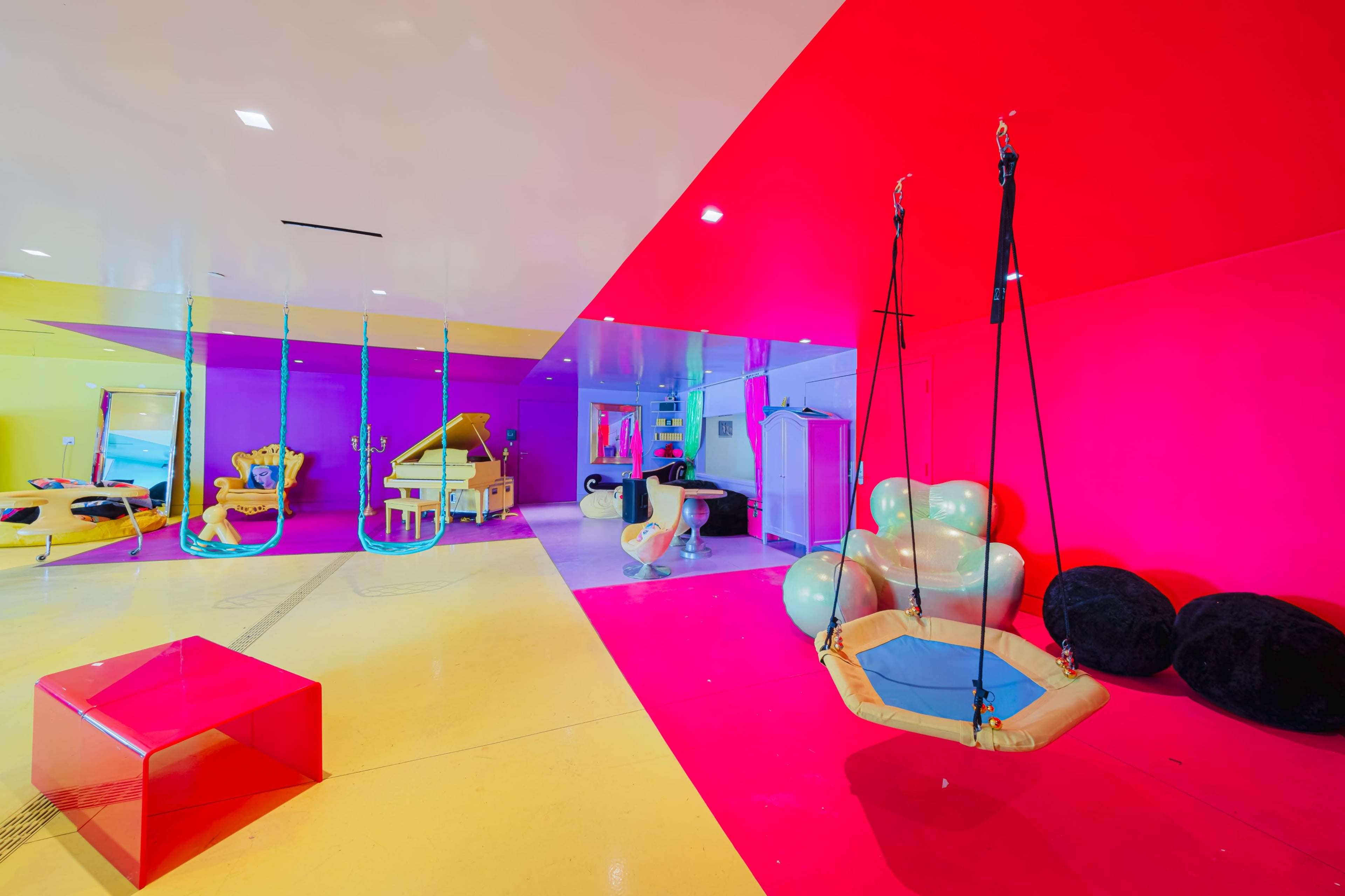 The scene features a vibrant playroom with colorful walls, a swing, and various playful furniture pieces.